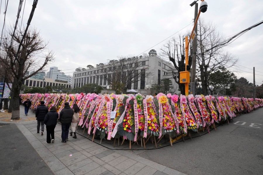 People walk past wreaths sent by supporters of impeached South Korean President Yoon Suk Yeol outside of the Constitutional Court in Seoul, South Korea, Friday, Dec. 20, 2024. (AP Photo/Ahn Young-joon)