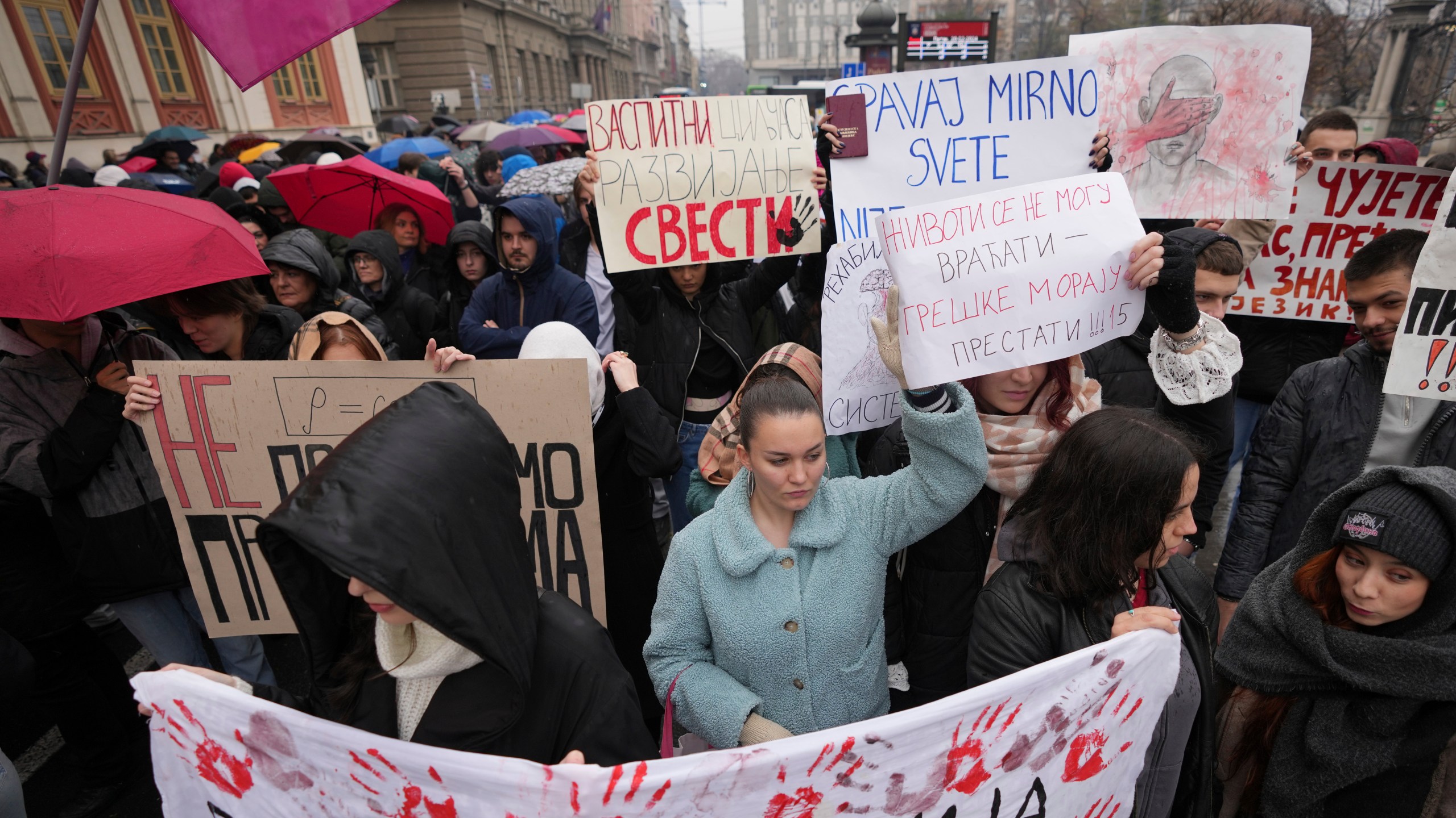 People stopping traffic, stand in silence during ongoing protests that erupted after a concrete canopy fell last month and killed 15 people, in Belgrade, Serbia, Friday, Dec. 20, 2024. (AP Photo/Darko Vojinovic)