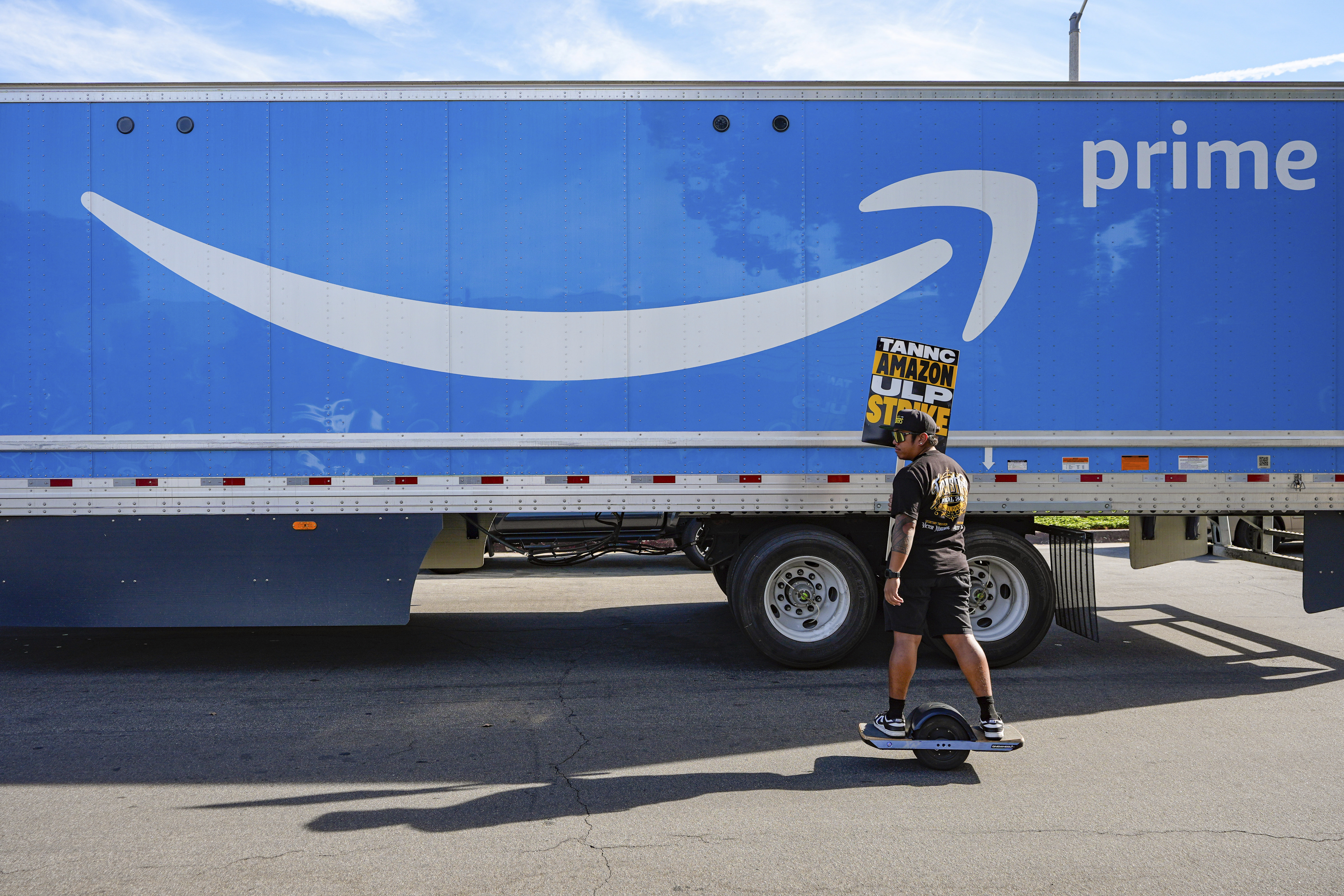 UPS driver Jhon Solidum, a member of the Teamsters union, rides a one wheeler to support the Amazon workers striking outside an Amazon Fulfillment Center as Teamsters seek labor contract nationwide, Thursday, Dec. 19, 2024, in City of Industry, Calif. (AP Photo/Damian Dovarganes)