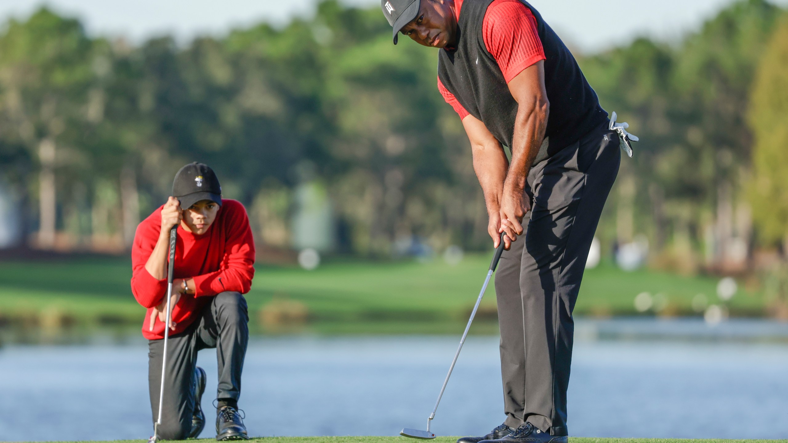 Charlie Woods, left, watches his father Tiger Woods, right, watches during the final round of the PNC Championship golf tournament, Dec. 18, 2022, in Orlando, Fla. (AP Photo/Kevin Kolczynski)