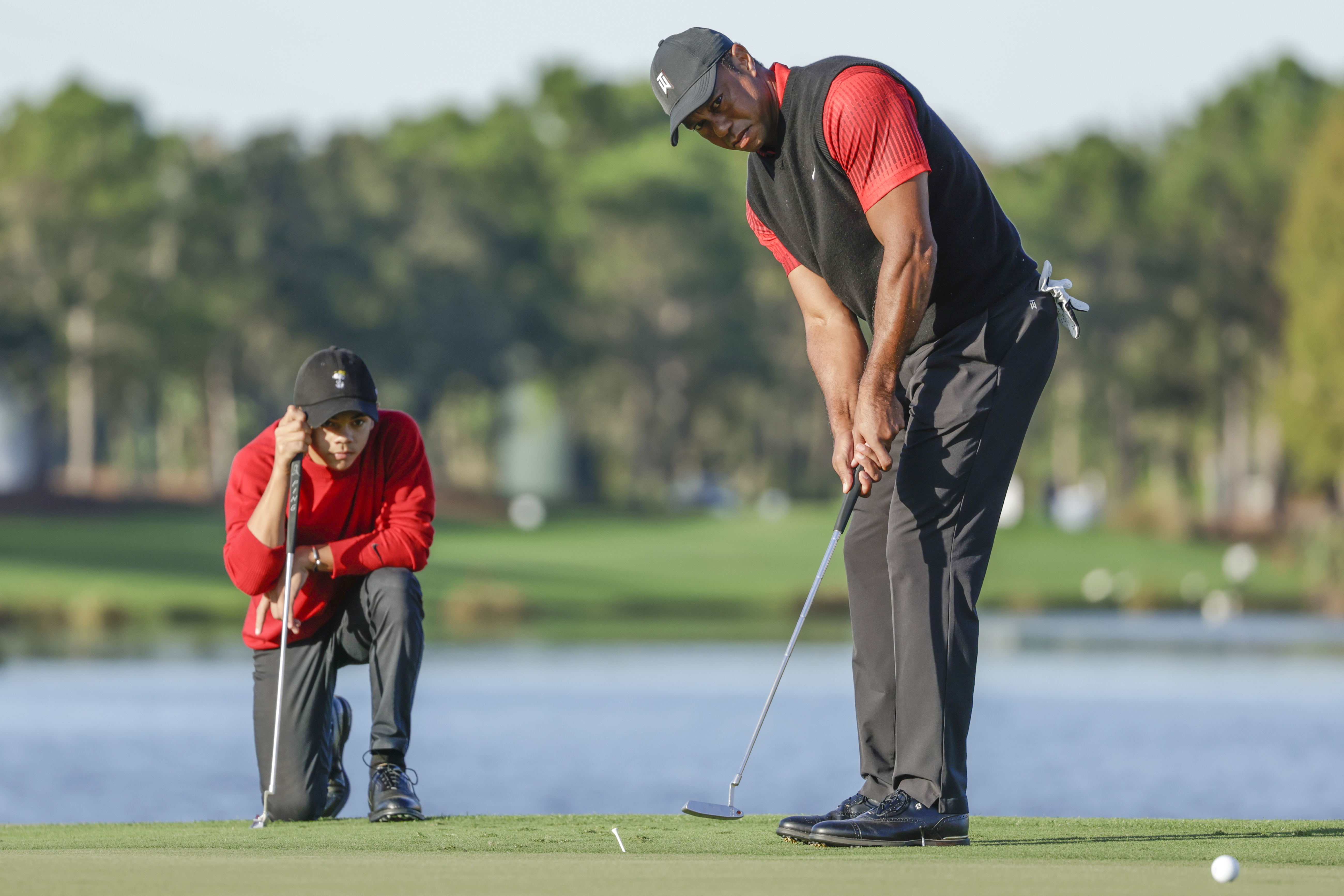 Charlie Woods, left, watches his father Tiger Woods, right, watches during the final round of the PNC Championship golf tournament, Dec. 18, 2022, in Orlando, Fla. (AP Photo/Kevin Kolczynski)