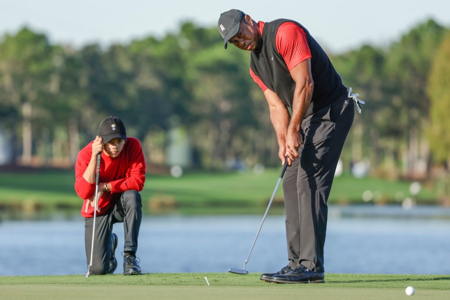 Charlie Woods, left, watches his father Tiger Woods, right, watches during the final round of the PNC Championship golf tournament, Dec. 18, 2022, in Orlando, Fla. (AP Photo/Kevin Kolczynski)