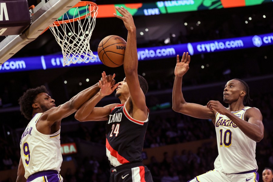 Los Angeles Lakers guard Bronny James, left, intercepts Portland Trail Blazers' forward Kris Murray, center, as he tries to score, next to Los Angeles Lakers center Christian Koloko during the second half of an NBA basketball game, Sunday, Dec. 8, 2024, in Los Angeles. (AP Photo/Etienne Laurent)