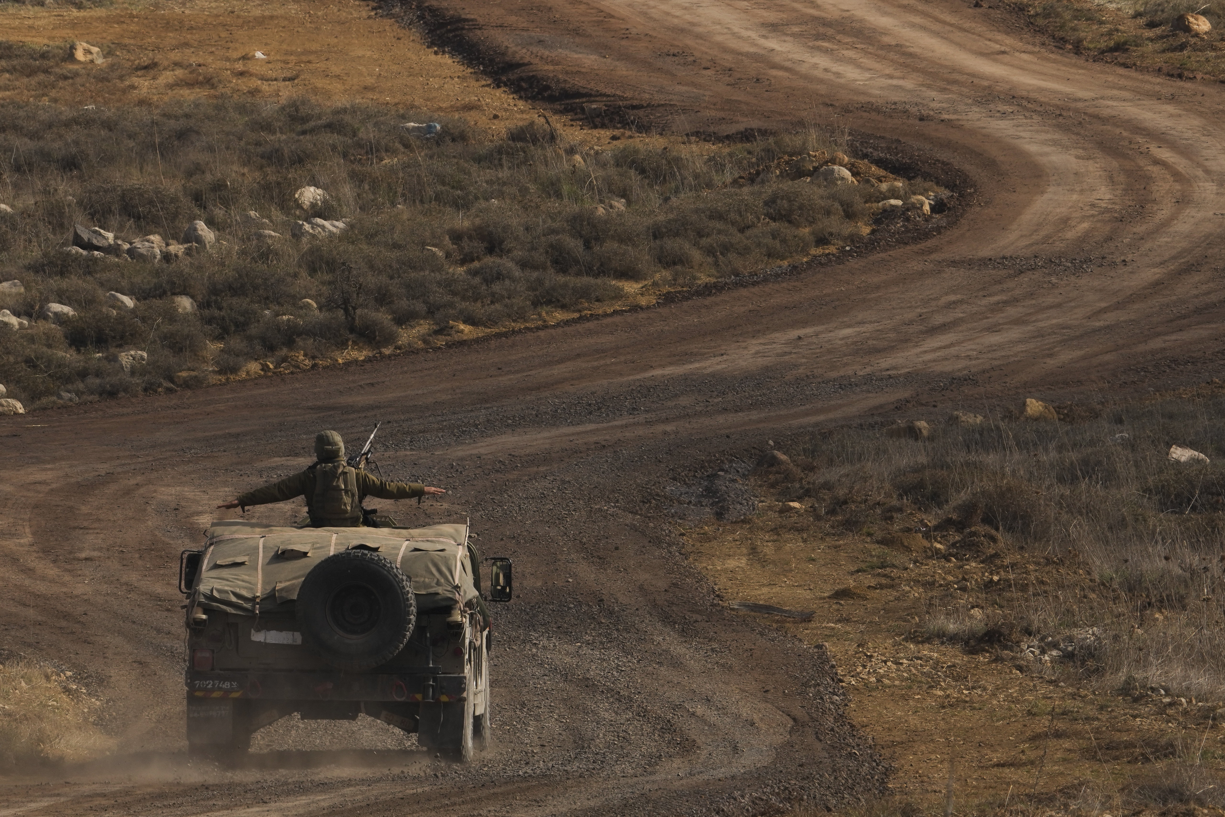 An Israeli soldier stands on an armoured vehicle on the buffer zone after crossing the security fence near the so-called Alpha Line that separates the Israeli-controlled Golan Heights from Syria, viewed from the town of Majdal Shams, Saturday, Dec. 21, 2024. (AP Photo/Matias Delacroix)