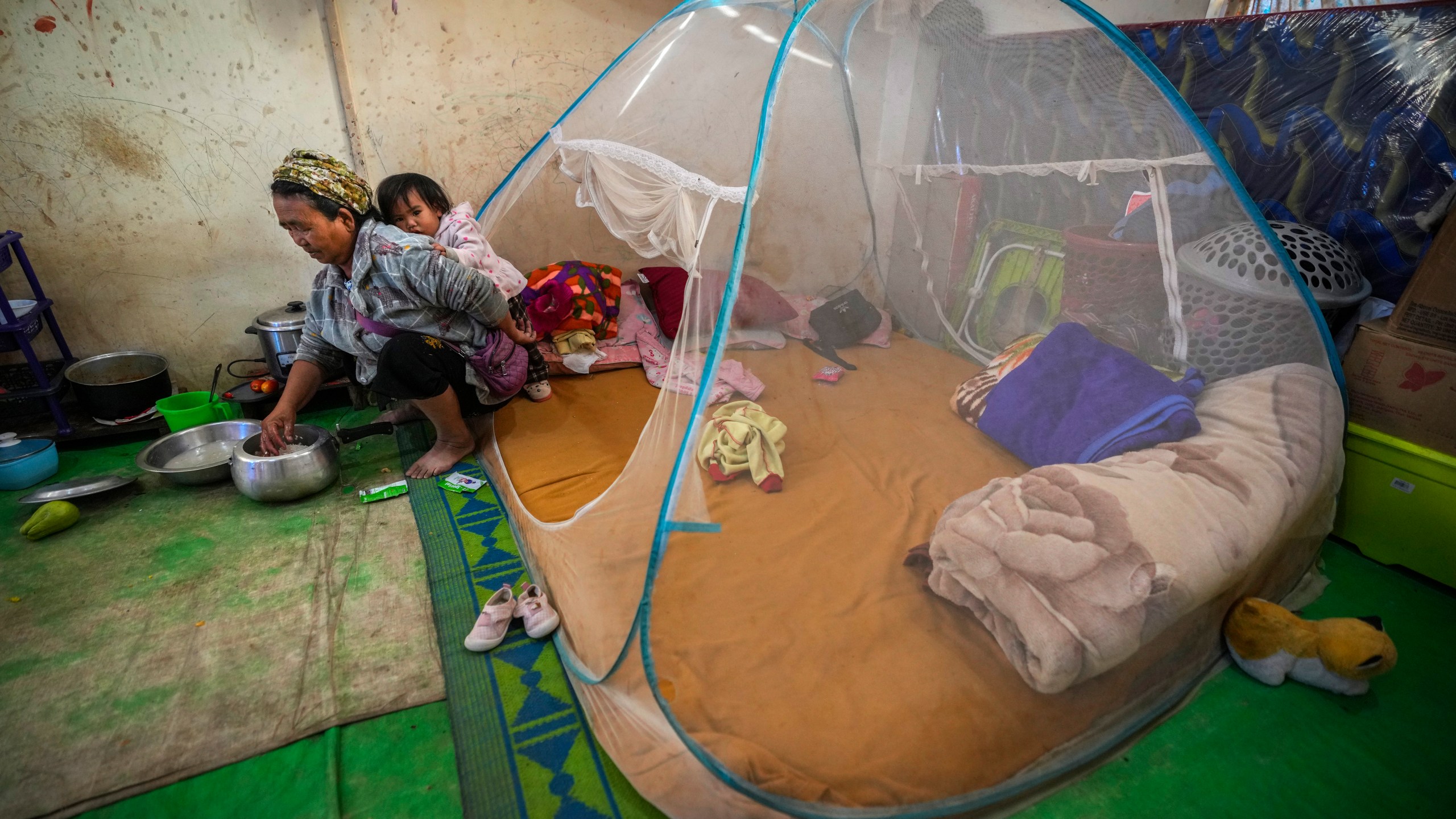 A Kuki tribal woman with a child prepares rice in a relief camp in Kangpokpi, Manipur, Sunday, Dec. 15, 2024. (AP Photo/Anupam Nath)