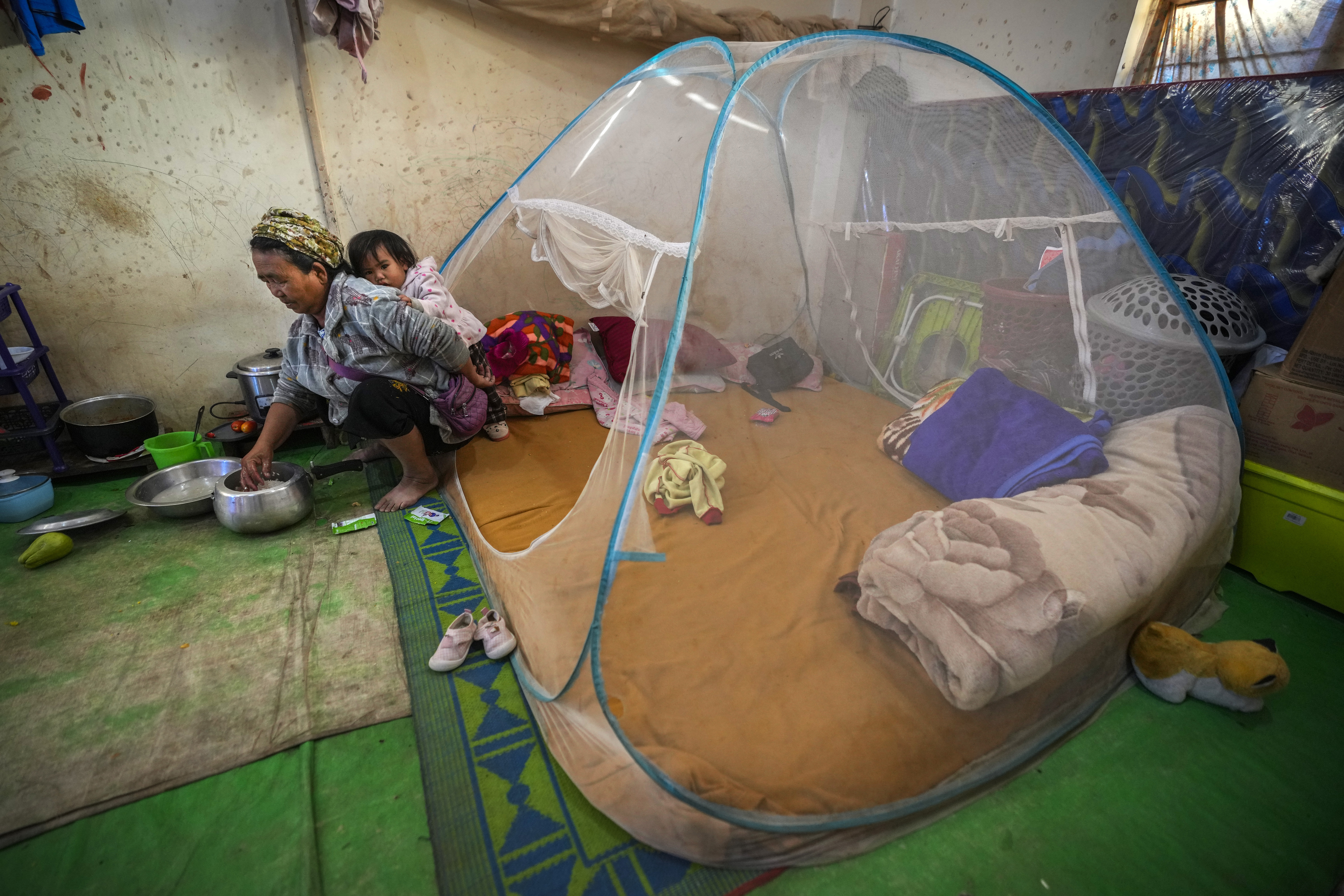 A Kuki tribal woman with a child prepares rice in a relief camp in Kangpokpi, Manipur, Sunday, Dec. 15, 2024. (AP Photo/Anupam Nath)