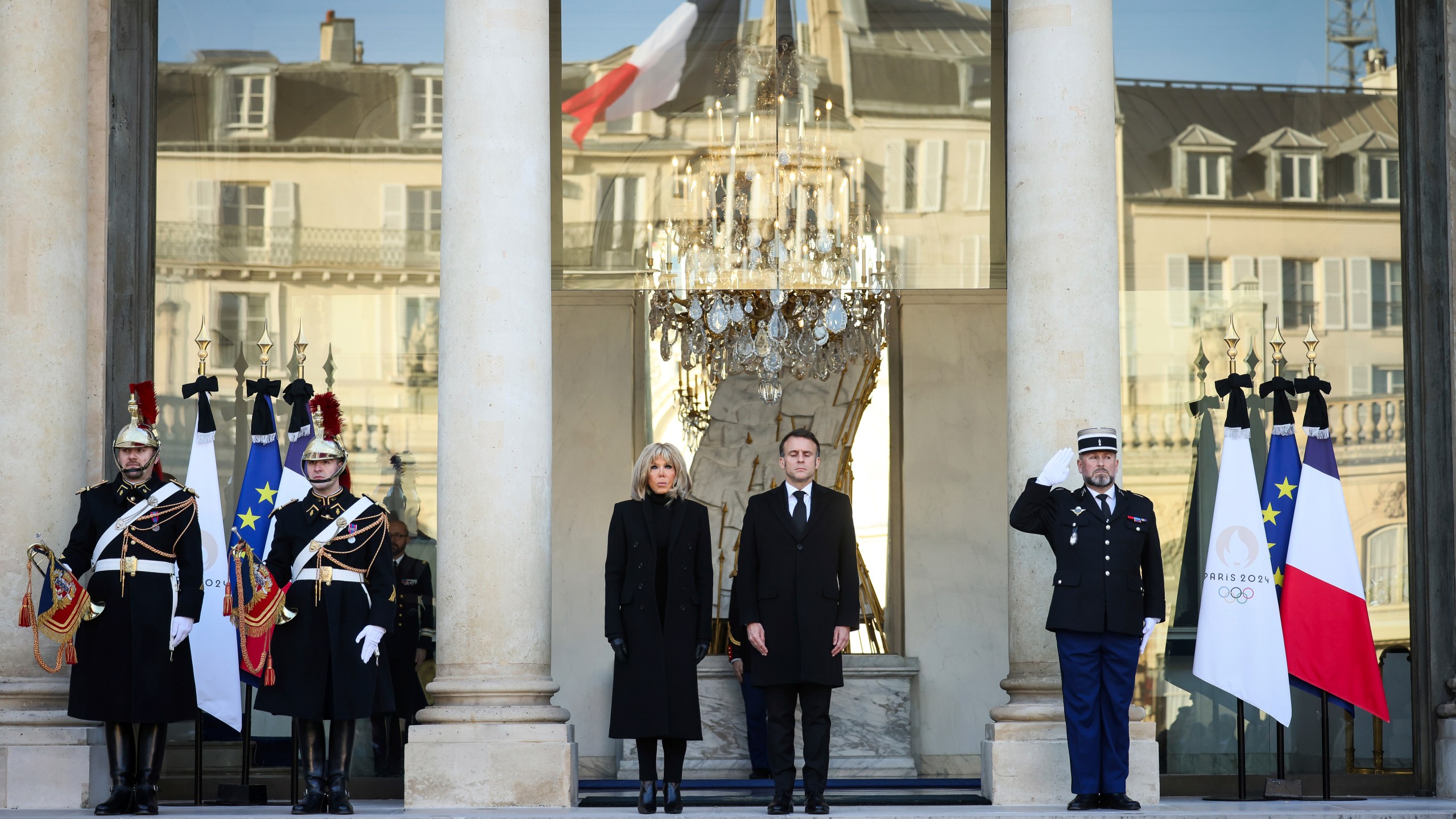 French President Emmanuel Macron and his wife Brigitte Macron stand for a minute of silence Monday, Dec. 23, 2024 at the Elysee Palace, where the French flag flies halfmast, in Paris, after Macron declared a day of national mourning for the lives lost when Cyclone Chido ripped through the Indian Ocean territory of Mayotte. (AP Photo/Thomas Padilla, Pool)