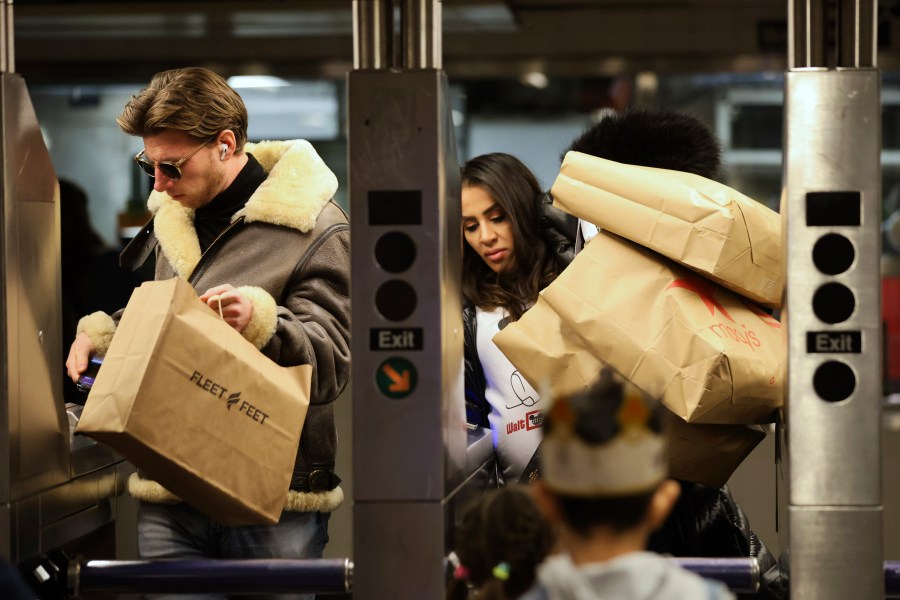 FILE - Shoppers manage their bags as they enter a subway turnstile, Nov. 29, 2024, in New York. (AP Photo/Heather Khalifa, File)