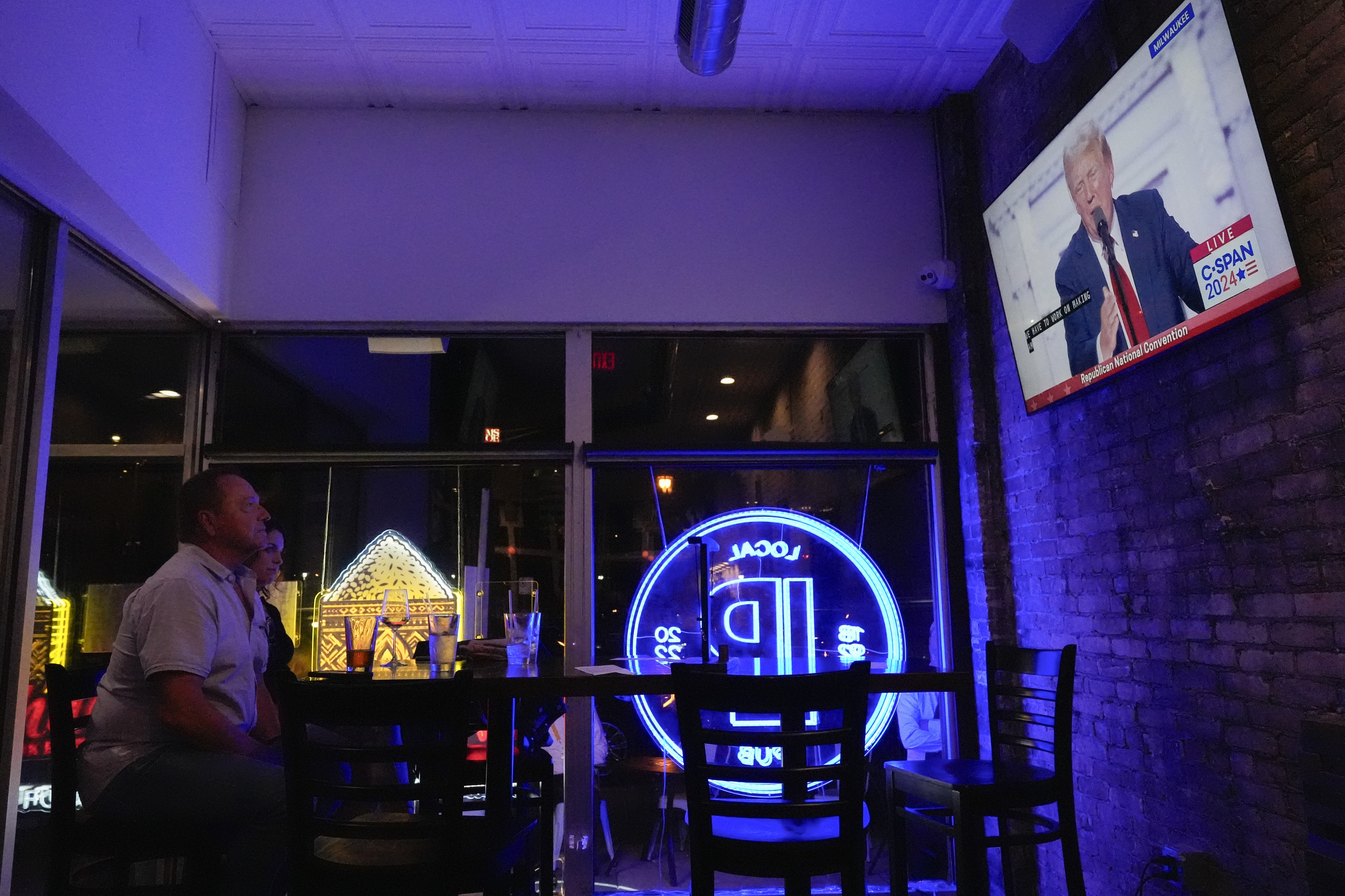 FILE - Jim, left, and Tamara Hamilton watch former President Donald Trump speak on television on Thursday, July 18, 2024, in Milwaukee. (AP Photo/Mike Stewart, File)