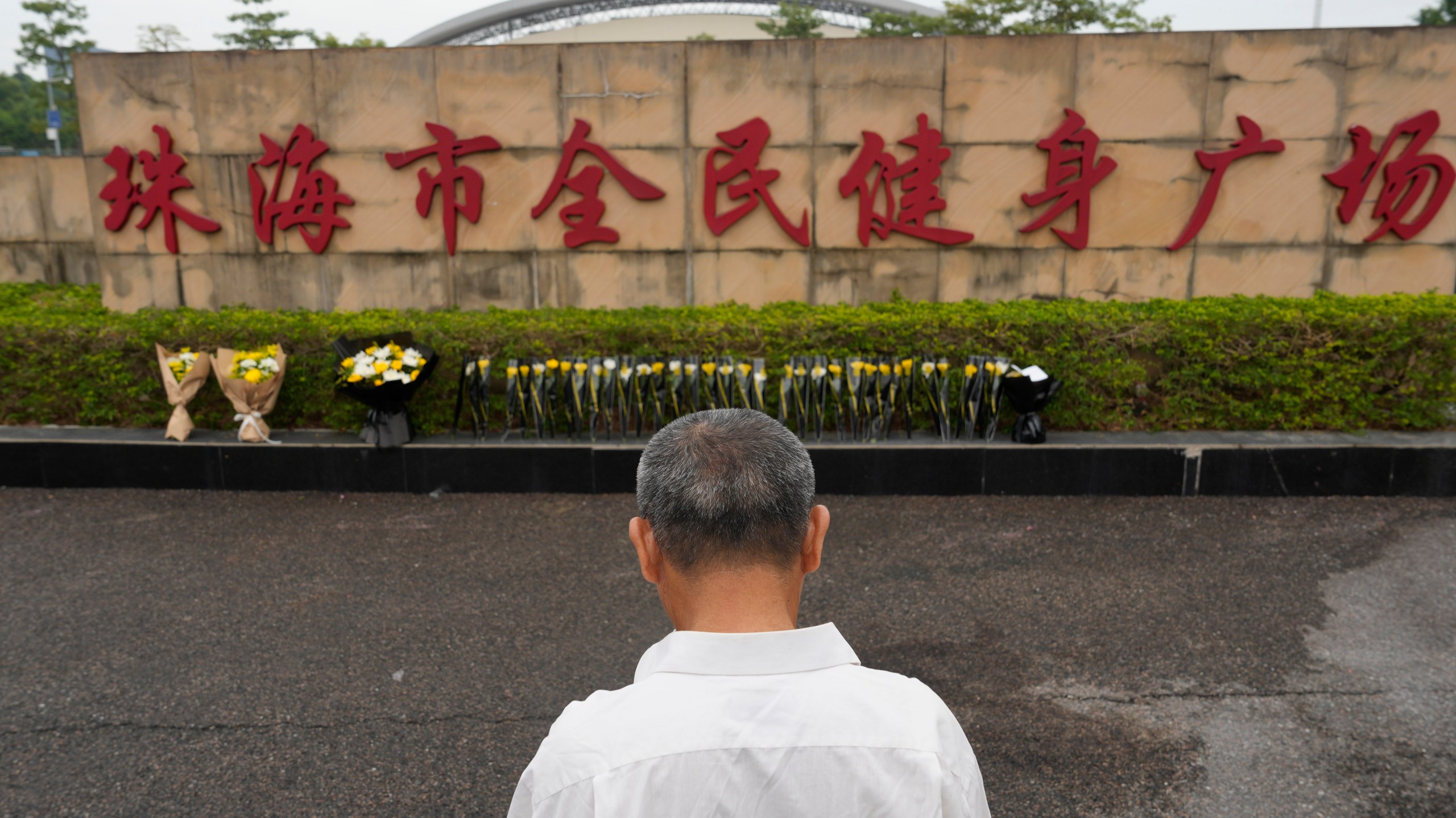 A man stands near flowers laid outside the Zhuhai People's Fitness Plaza, where a man rammed his car into people exercising at the sports center, in Zhuhai in southern China's Guangdong province on Wednesday, Nov. 13, 2024. (AP Photo/Ng Han Guan, File)