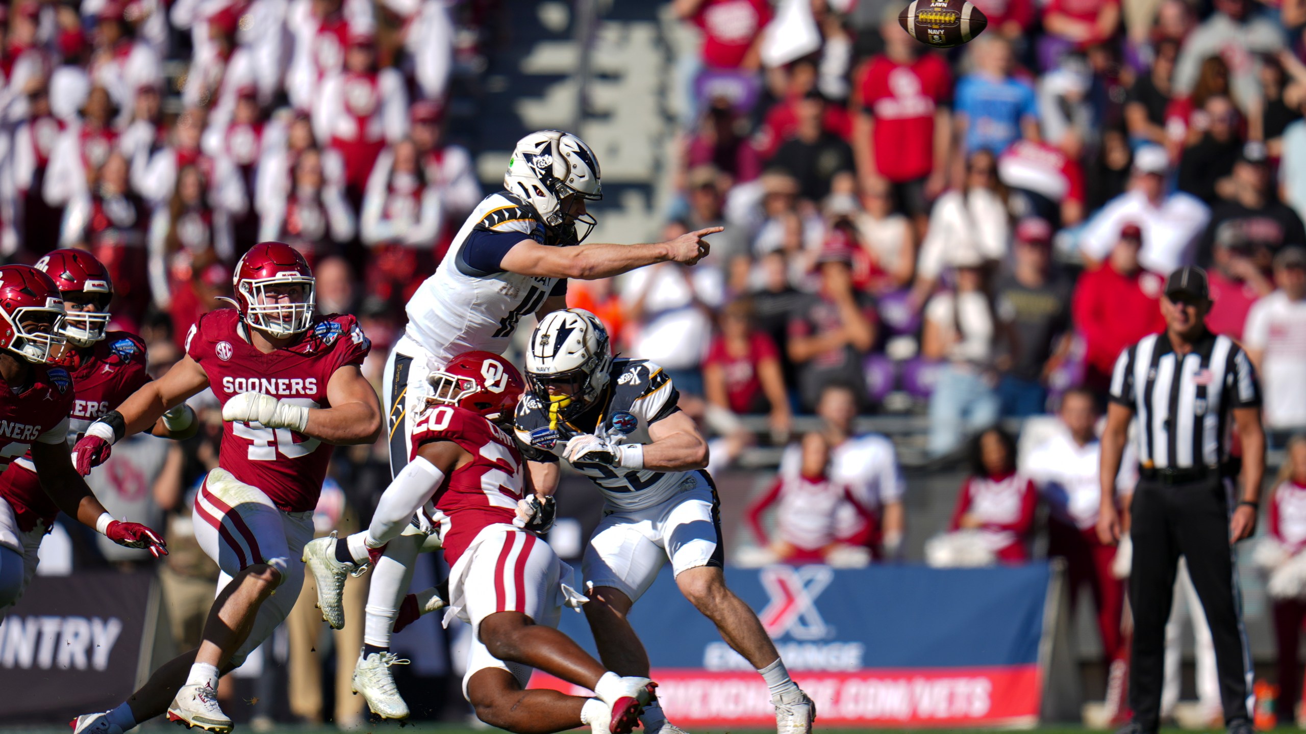 Navy quarterback Blake Horvath, top left, takes a hit from Oklahoma linebacker Lewis Carter (20) while attempting a pass during the first half of the Armed Forces Bowl NCAA college football game, Friday, Dec. 27, 2024, in Fort Worth, Texas. (AP Photo/Julio Cortez)