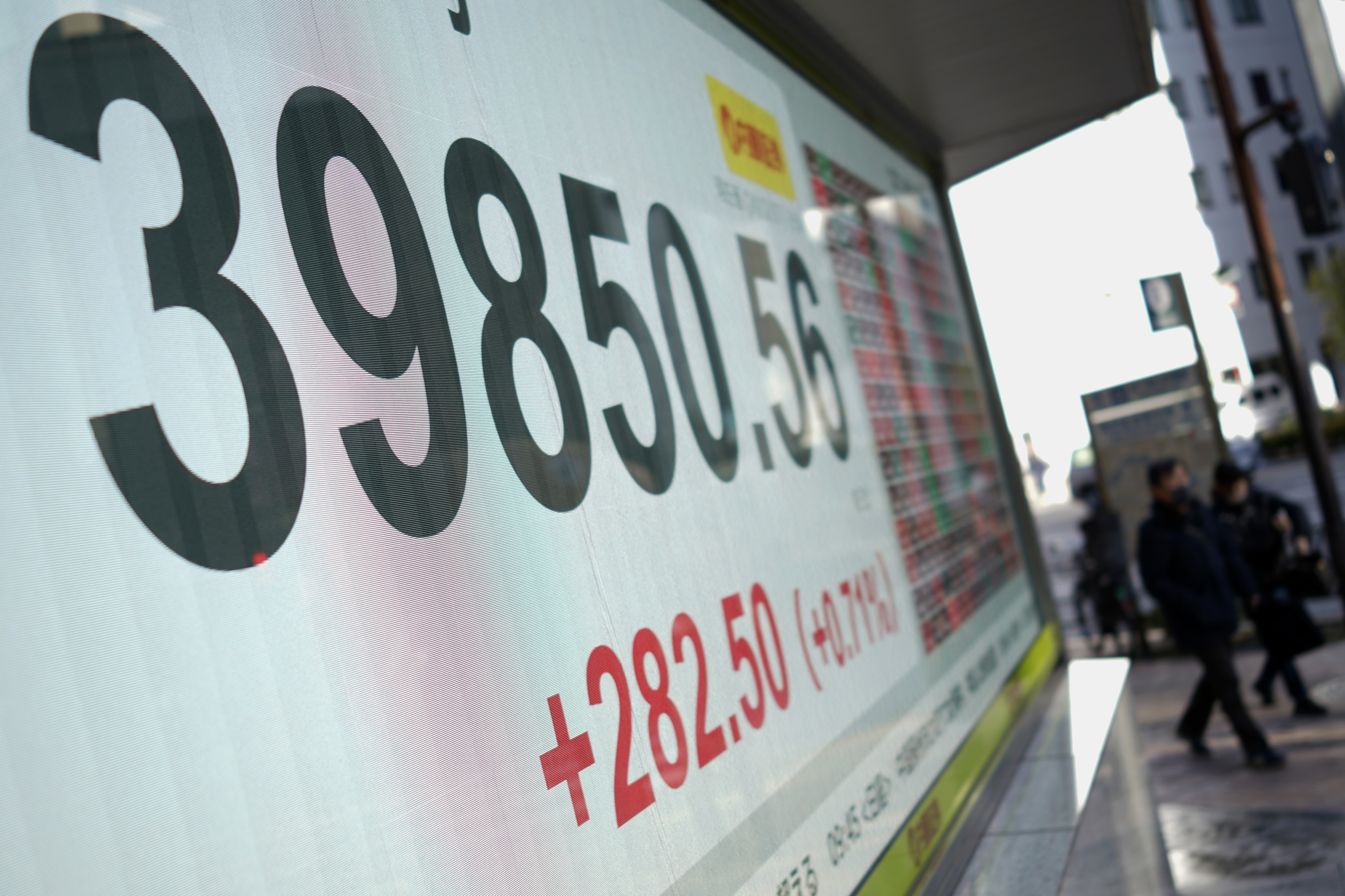 People walk in front of an electronic stock board showing Japan's Nikkei index at a securities firm Friday, Dec. 27, 2024, in Tokyo. (AP Photo/Eugene Hoshiko)