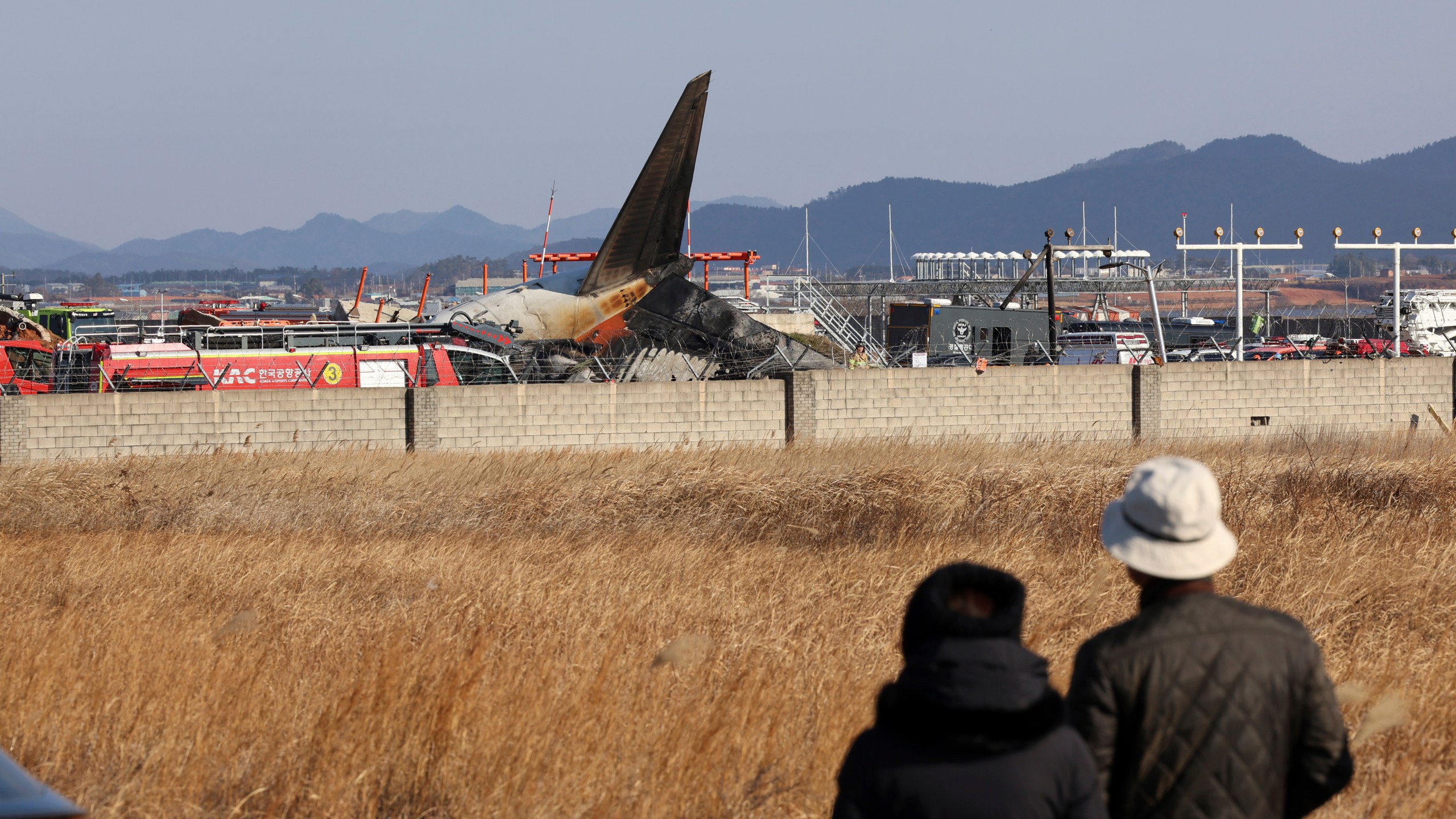 People watch as firefighters and rescue team members work at Muan International Airport in Muan, South Korea, Sunday, Dec. 29, 2024. (Cho Nam-soo/Yonhap via AP)