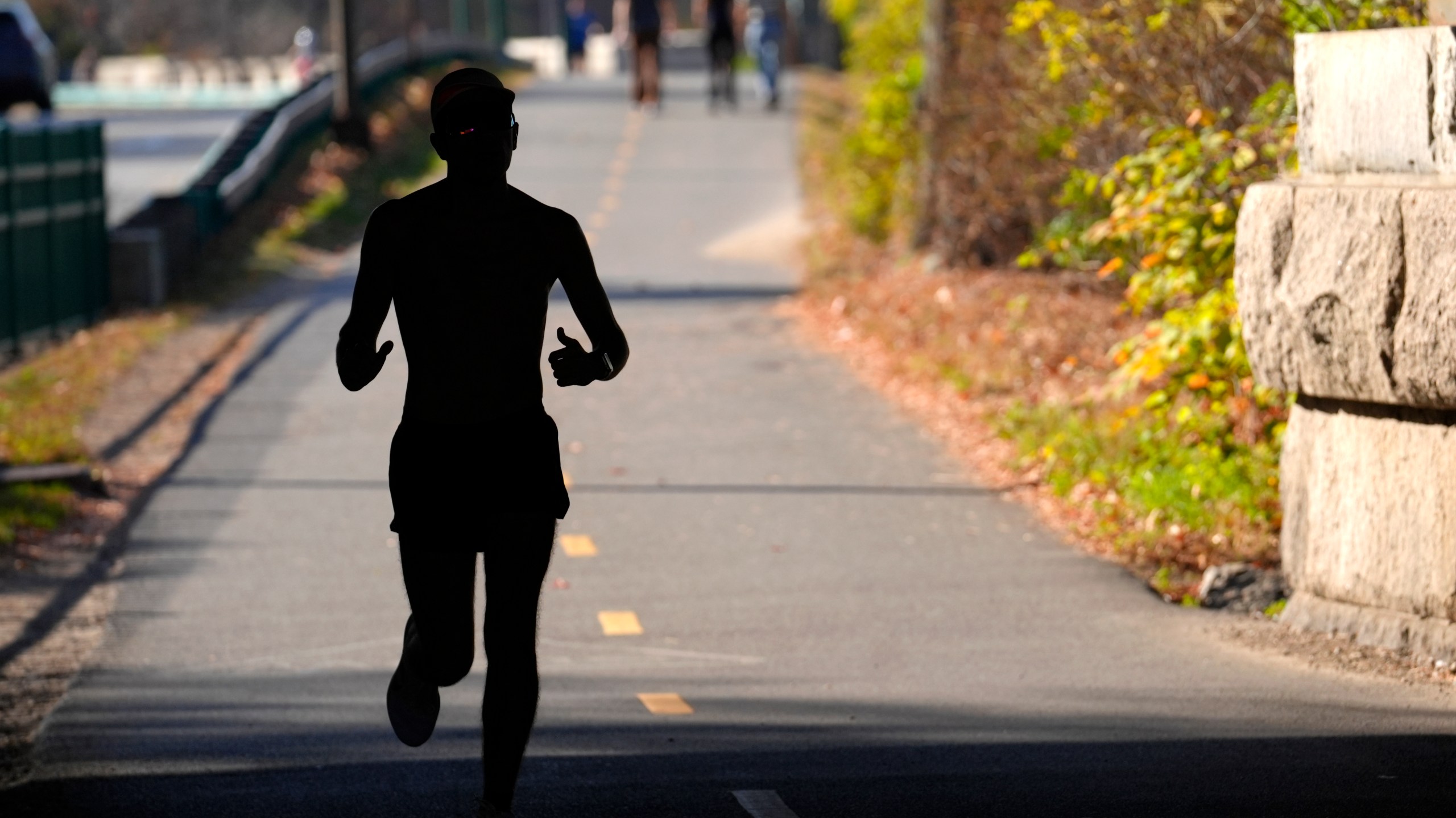 FILE - A runner appears in silhouette while running in temperatures in the 70s, Wednesday, Nov. 6, 2024, under a bridge near the Charles River, in Boston. (AP Photo/Steven Senne, File)