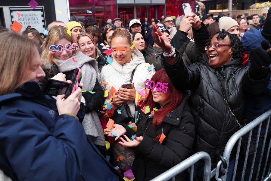 People in the crowd pose for photos with confetti ahead of New Year's Eve in Times Square, Sunday, Dec. 29, 2024, in New York. (AP Photo/Heather Khalifa)