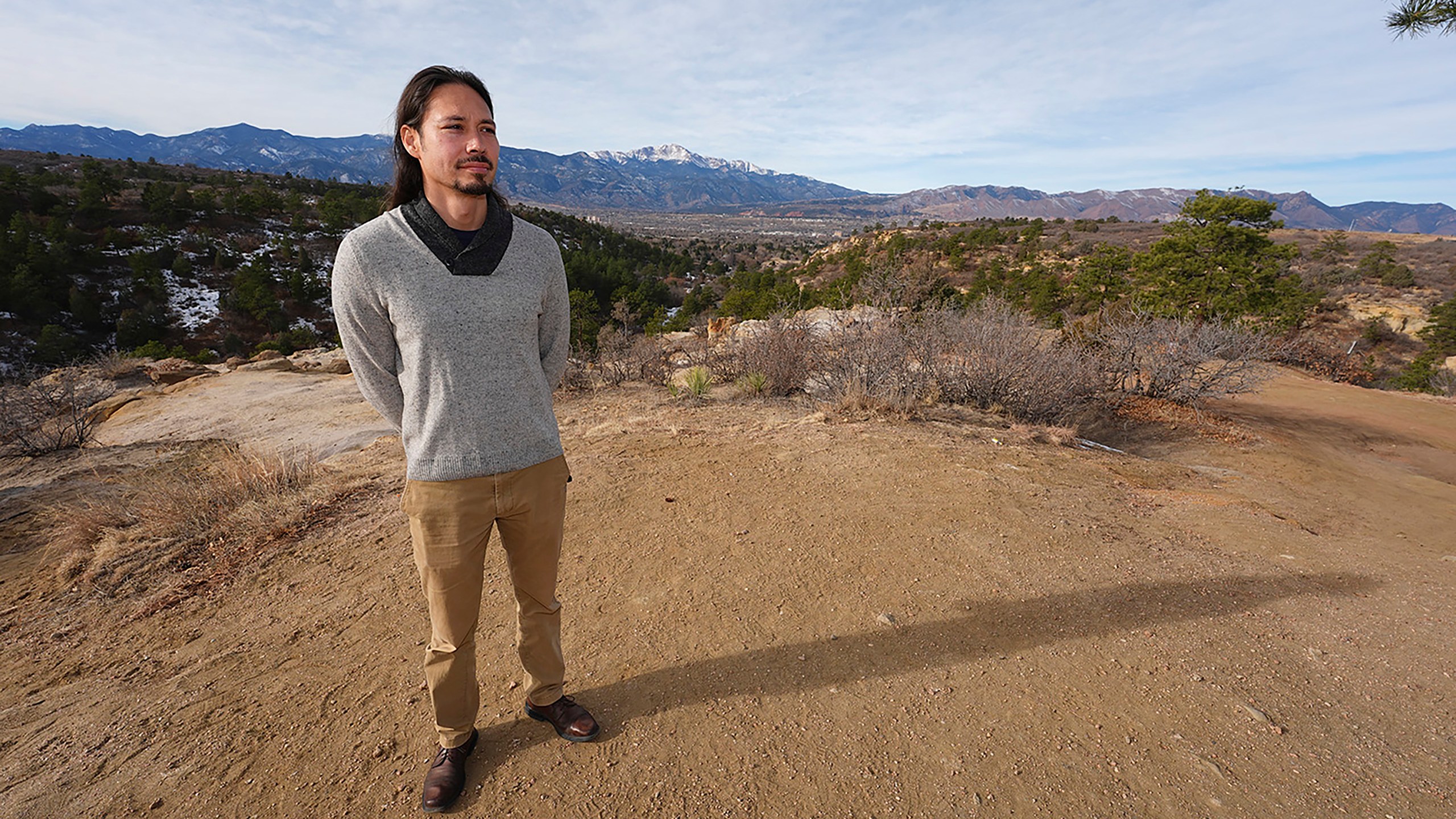 Lane Belone poses with Pikes Peak in the background on an overlook in Palmer Park, Thursday, Dec. 19, 2024, in Colorado Springs, Colo. (AP Photo/David Zalubowski)