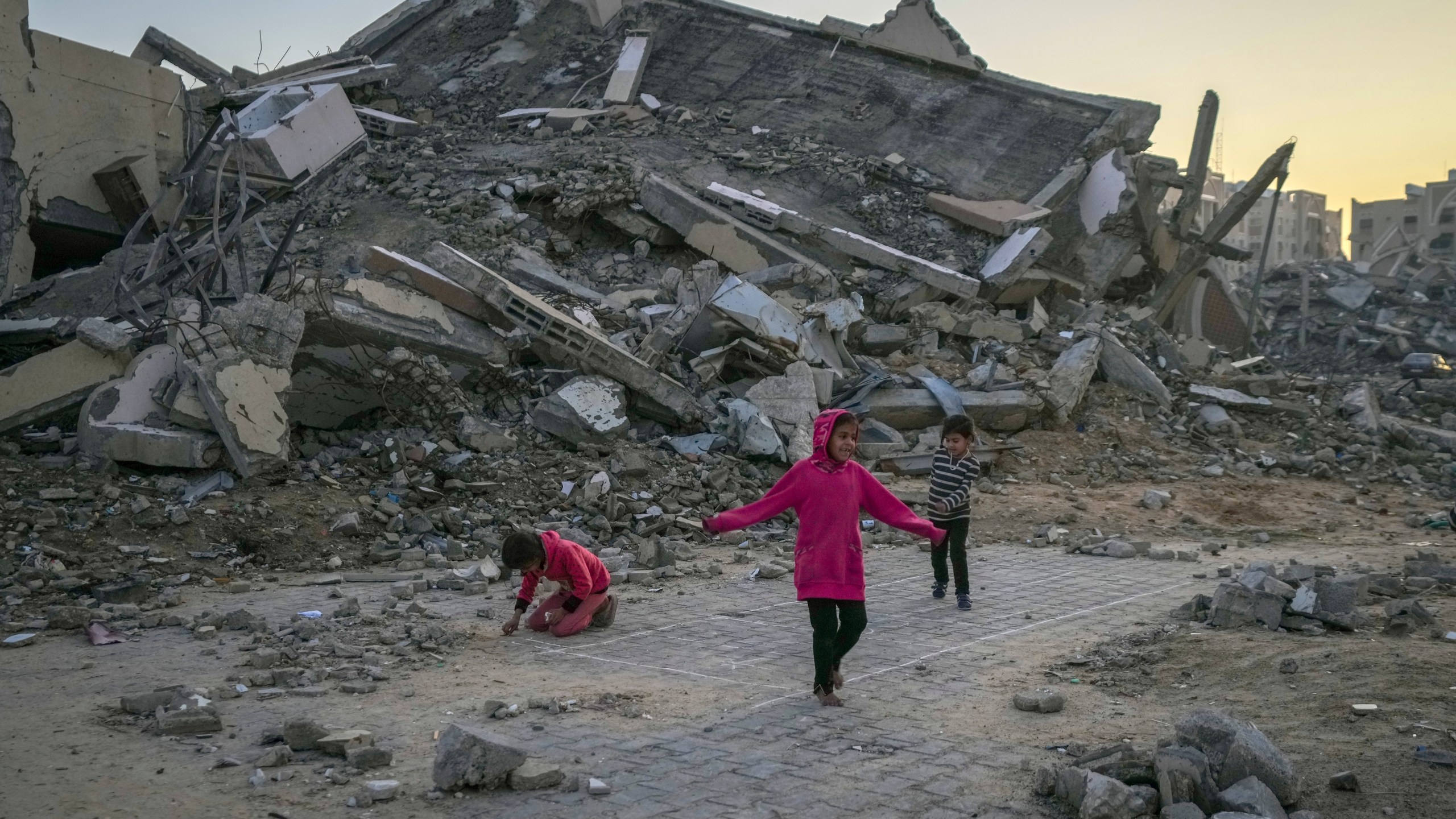 Palestinian children play next to a building destroyed by Israeli army strikes in the central Gaza Strip town of Khan Younis, Wednesday, Jan. 1, 2025. (AP Photo/Abdel Kareem Hana)