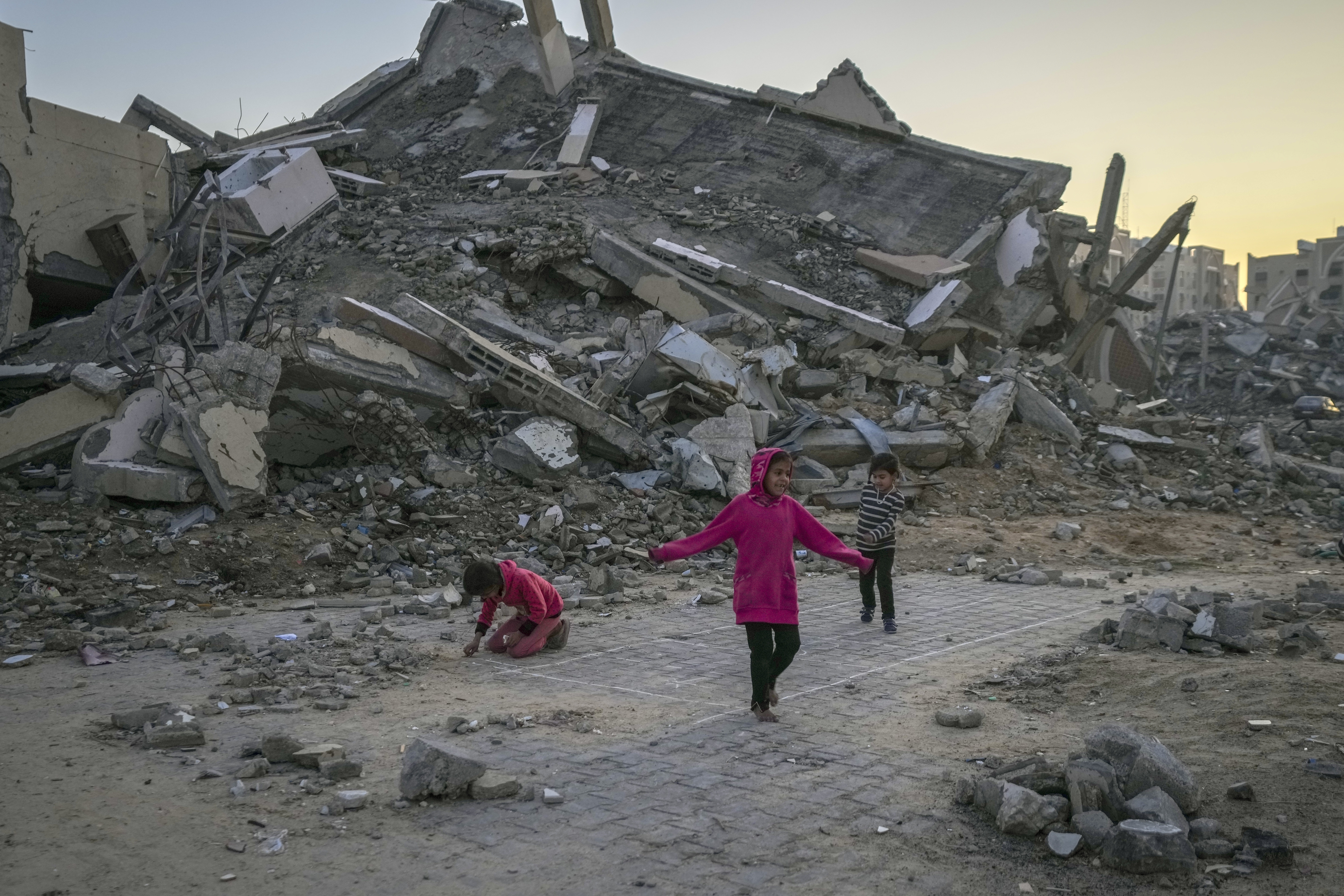 Palestinian children play next to a building destroyed by Israeli army strikes in the central Gaza Strip town of Khan Younis, Wednesday, Jan. 1, 2025. (AP Photo/Abdel Kareem Hana)