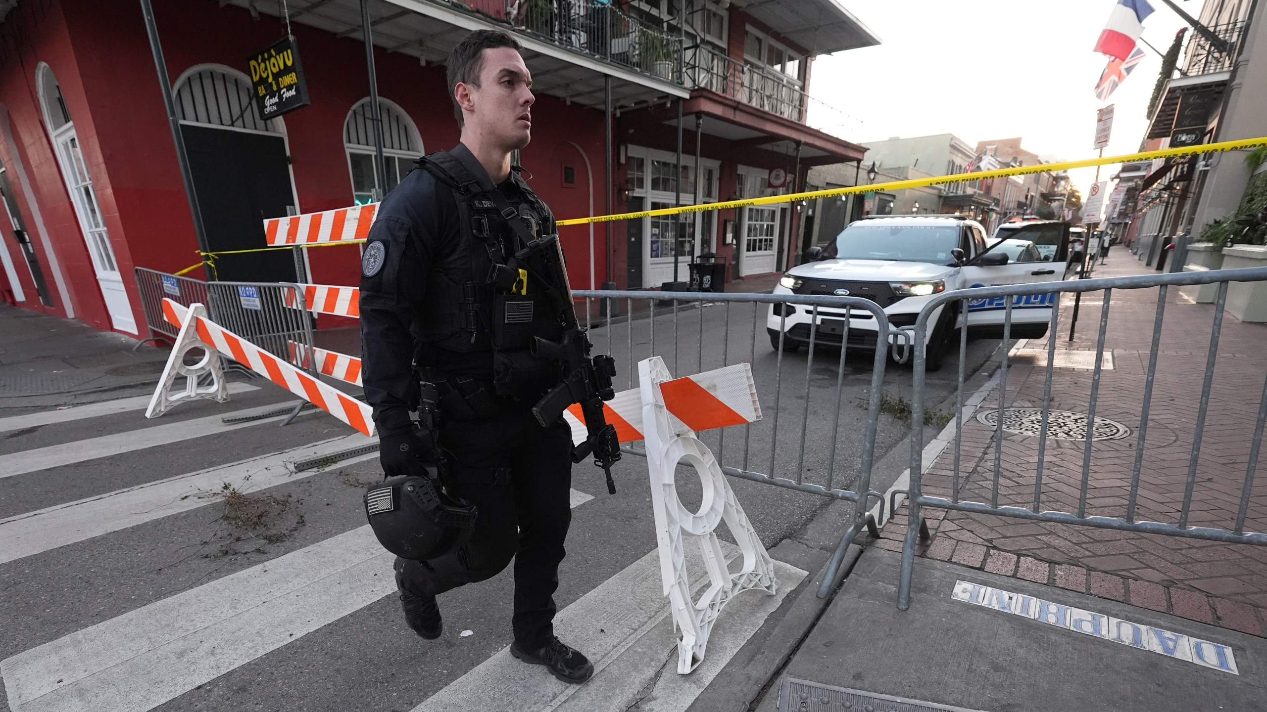 A member of the emergency services walks past a police barricade after a vehicle drove into a crowd on New Orleans' Canal and Bourbon Street, Wednesday Jan. 1, 2025. (AP Photo/Gerald Herbert)