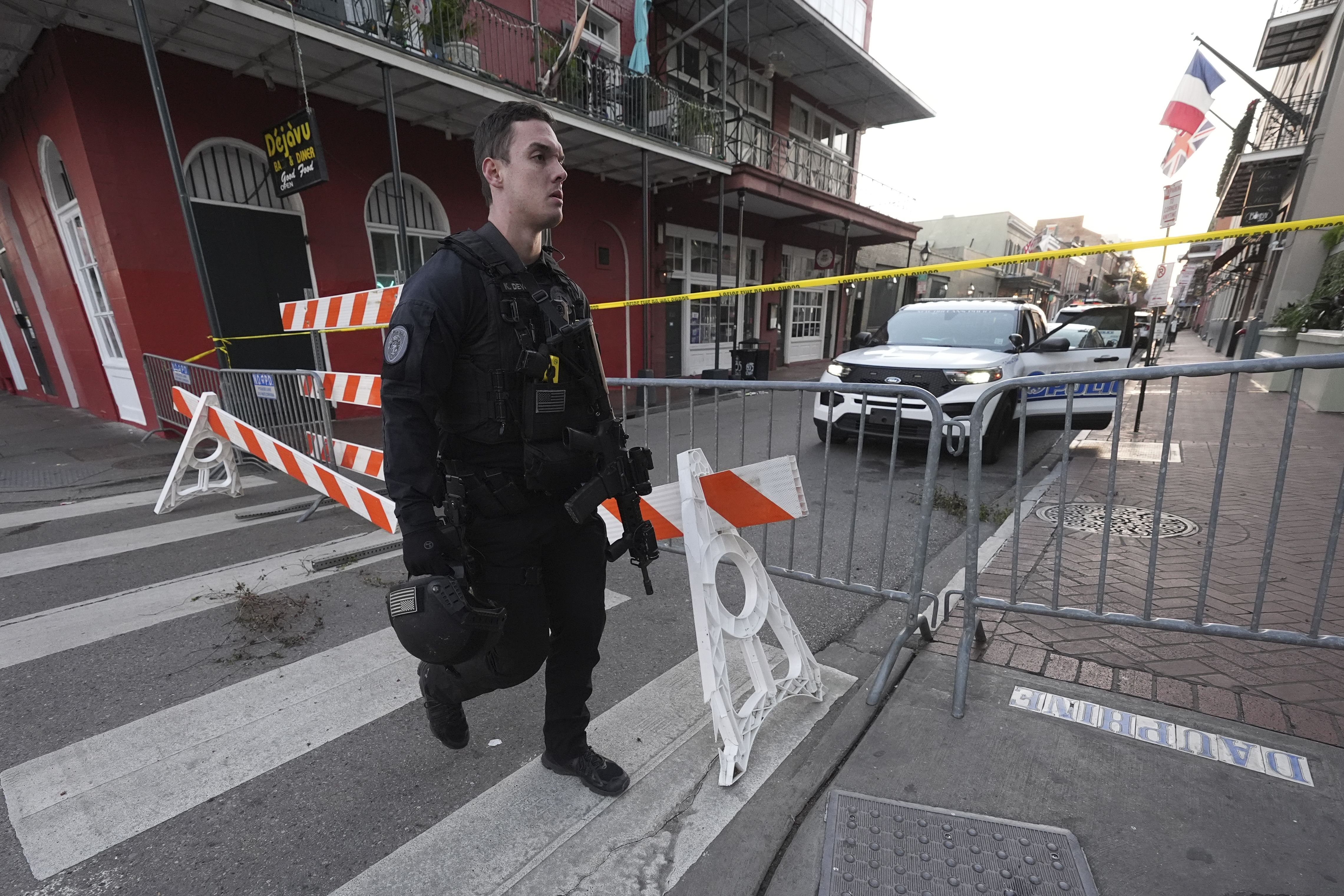 A member of the emergency services walks past a police barricade after a vehicle drove into a crowd on New Orleans' Canal and Bourbon Street, Wednesday Jan. 1, 2025. (AP Photo/Gerald Herbert)