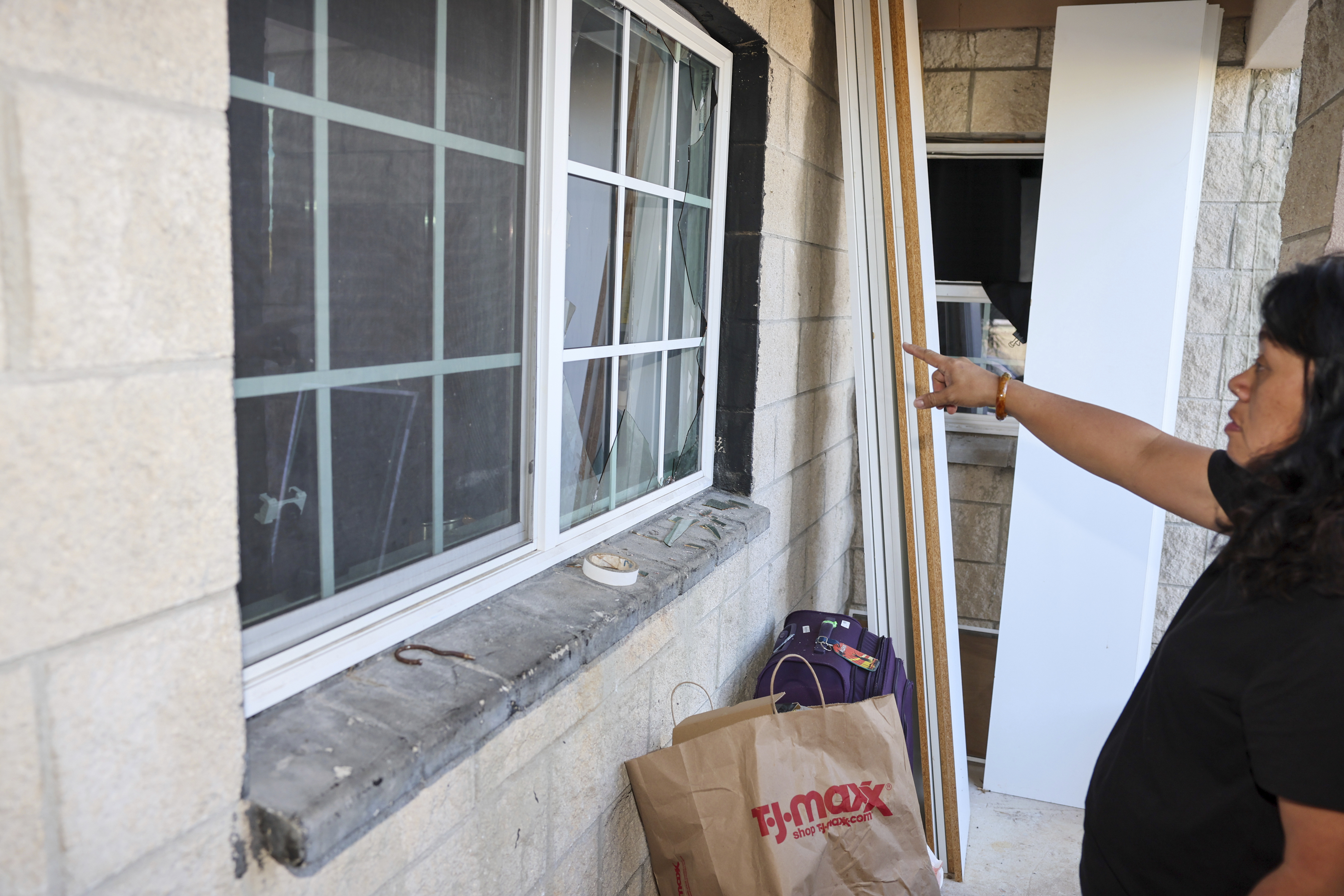 Evelyn Paguirigan points to broken windows at her home across the street from where a New Year's Eve fireworks explosion killed and injured people in Honolulu, on Wednesday, Jan. 1, 2025. (AP Photo/Marco Garcia)