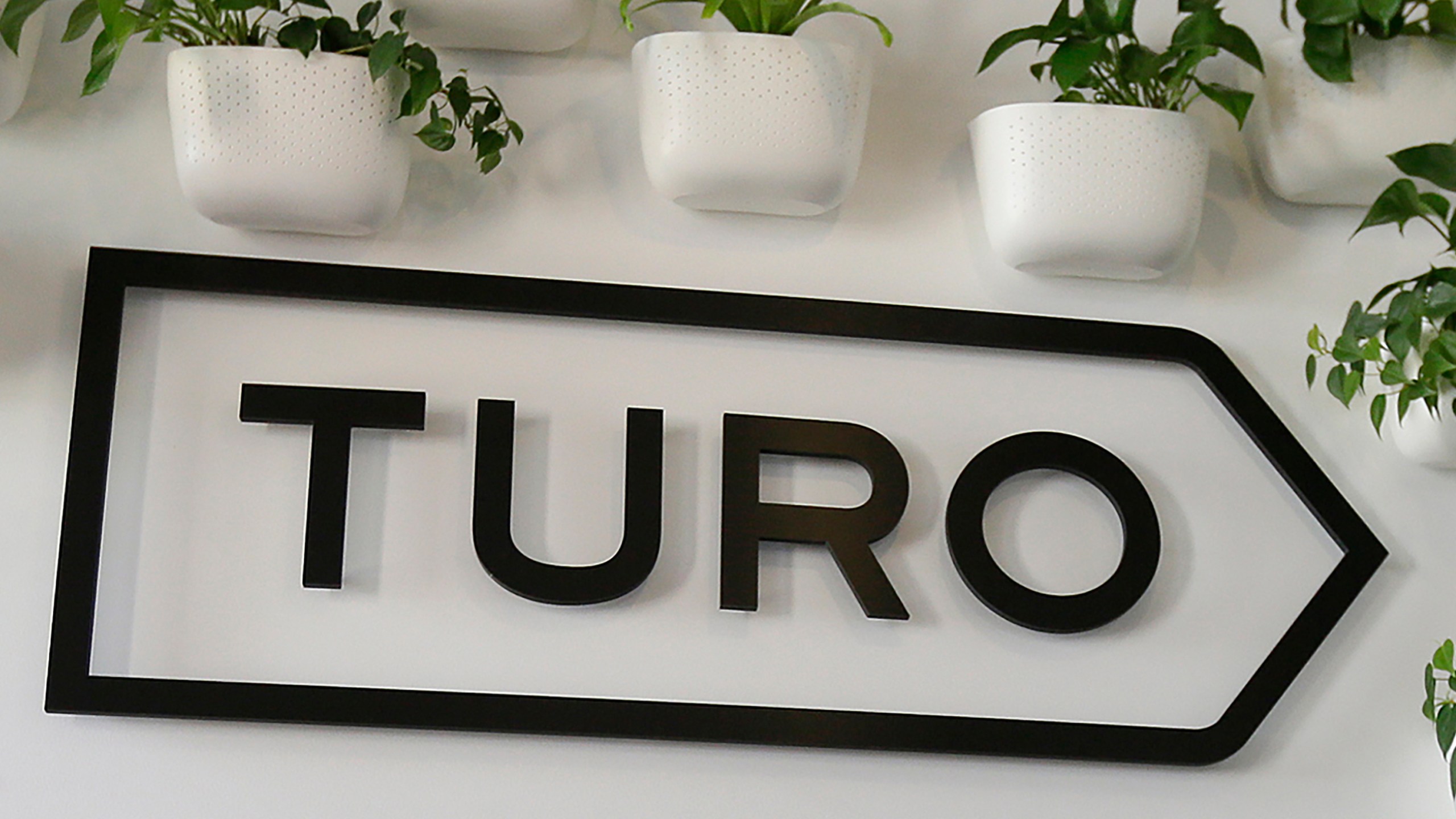 FILE - The Turo logo is shown in the entryway of Turo in San Francisco, April 29, 2019. (AP Photo/Eric Risberg, File)