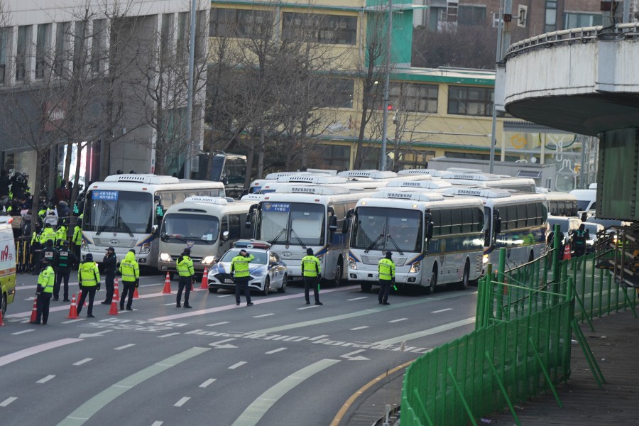 Police vehicles are seen near the gate of the presidential residence as supporters of impeached South Korean President Yoon Suk Yeol stage a rally to oppose a court having issued a warrant to detain Yoon, in Seoul, South Korea, Friday, Jan. 3, 2025. (AP Photo/Lee Jin-man)