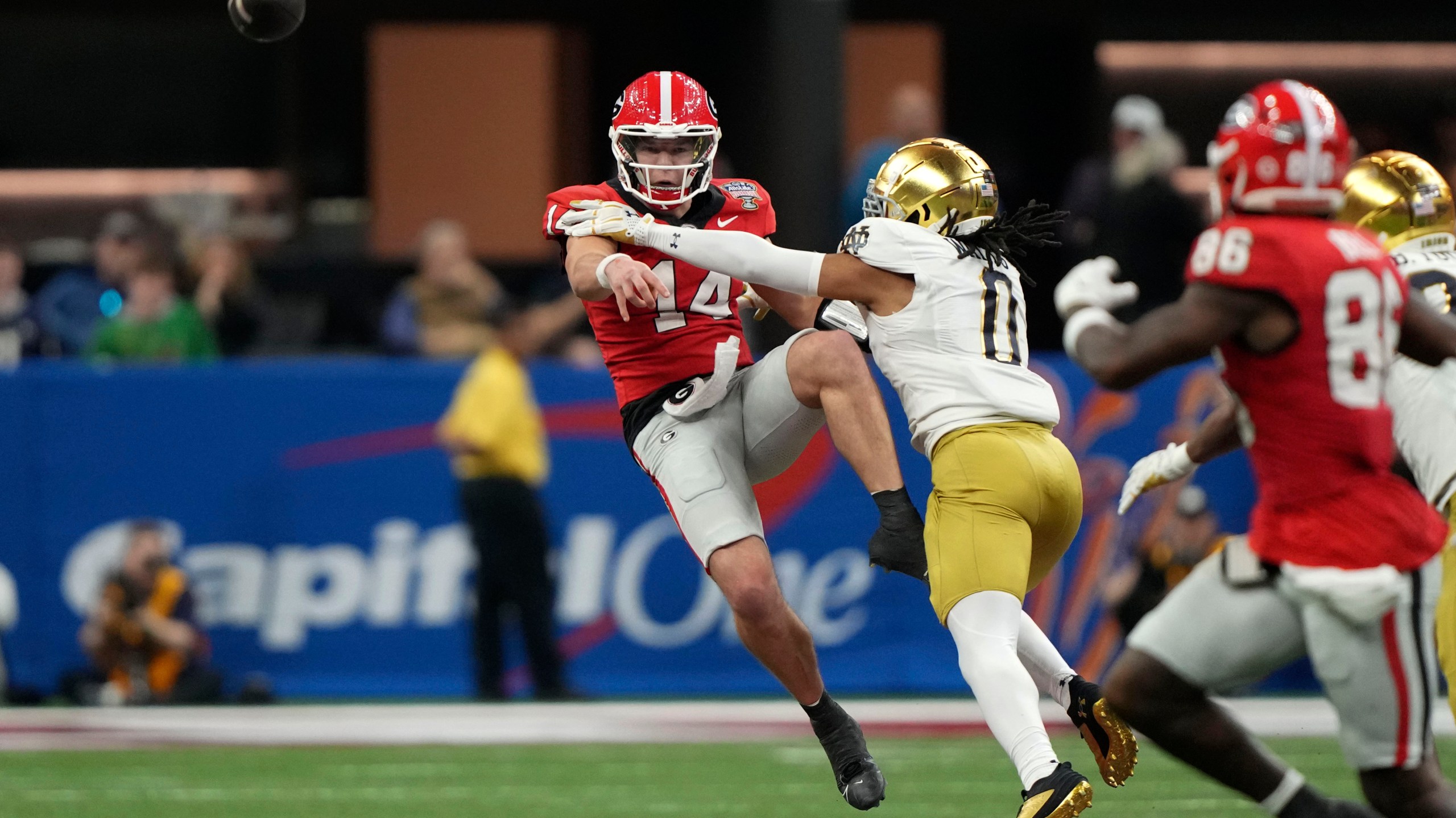 Georgia quarterback Gunner Stockton (14) throws a pass as he is pressured by Notre Dame safety Xavier Watts (0) during the second half in the quarterfinals of a College Football Playoff, Thursday, Jan. 2, 2025, in New Orleans. (AP Photo/Gerald Herbert)