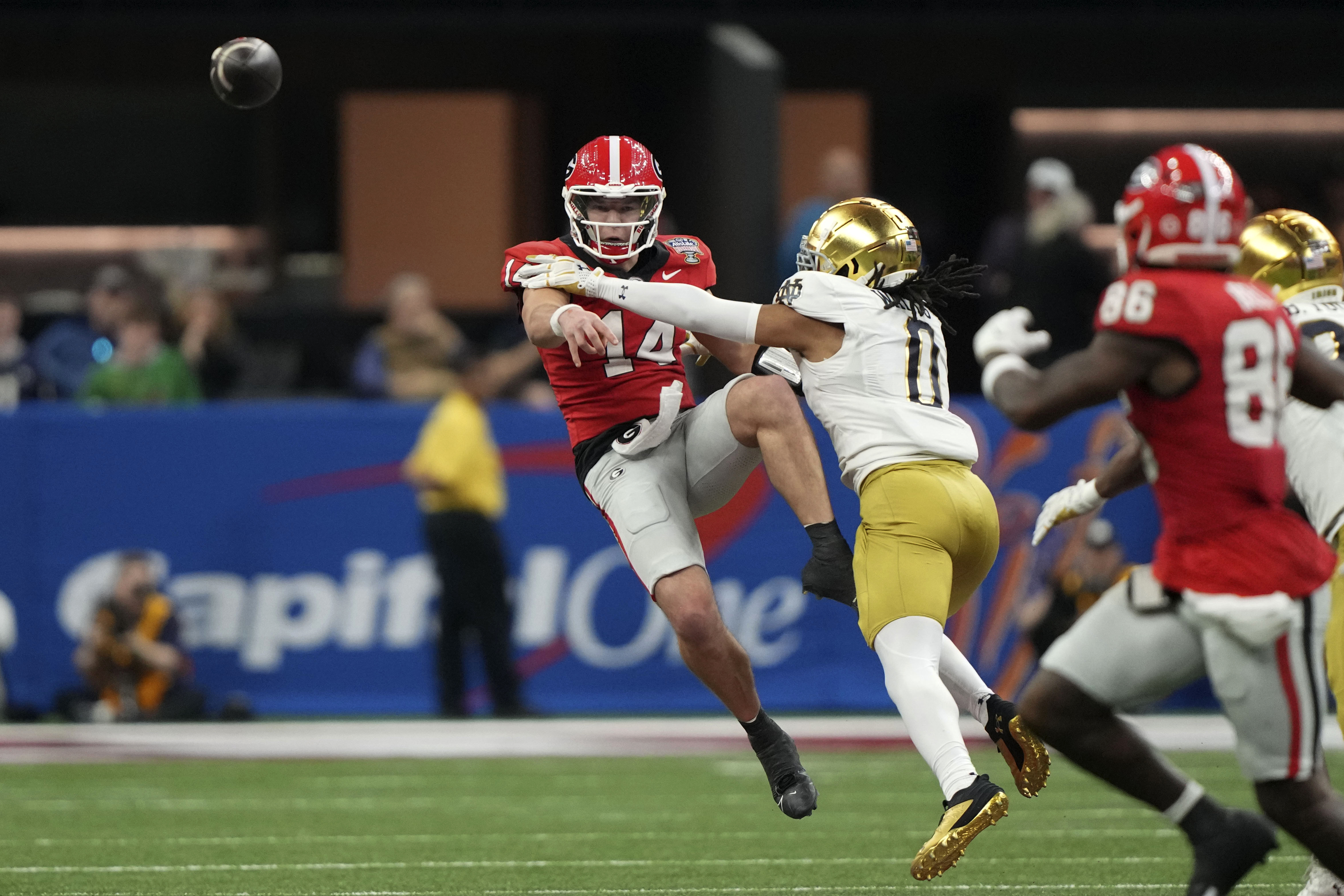 Georgia quarterback Gunner Stockton (14) throws a pass as he is pressured by Notre Dame safety Xavier Watts (0) during the second half in the quarterfinals of a College Football Playoff, Thursday, Jan. 2, 2025, in New Orleans. (AP Photo/Gerald Herbert)