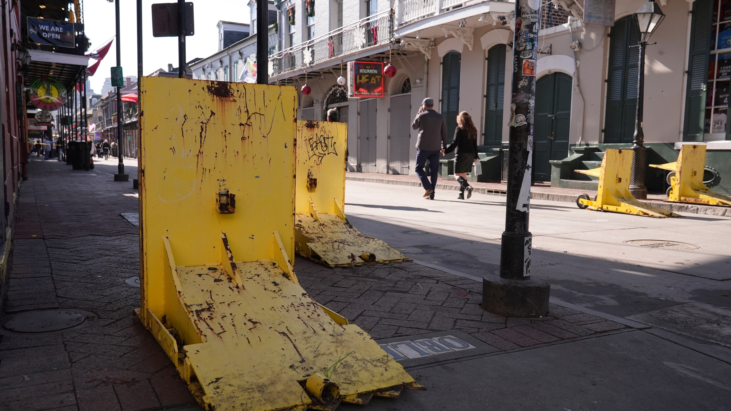 Tourist walk past temporary barriers on Bourbon Street, Thursday, Jan. 2, 2025 in New Orleans. (AP Photo/George Walker IV)