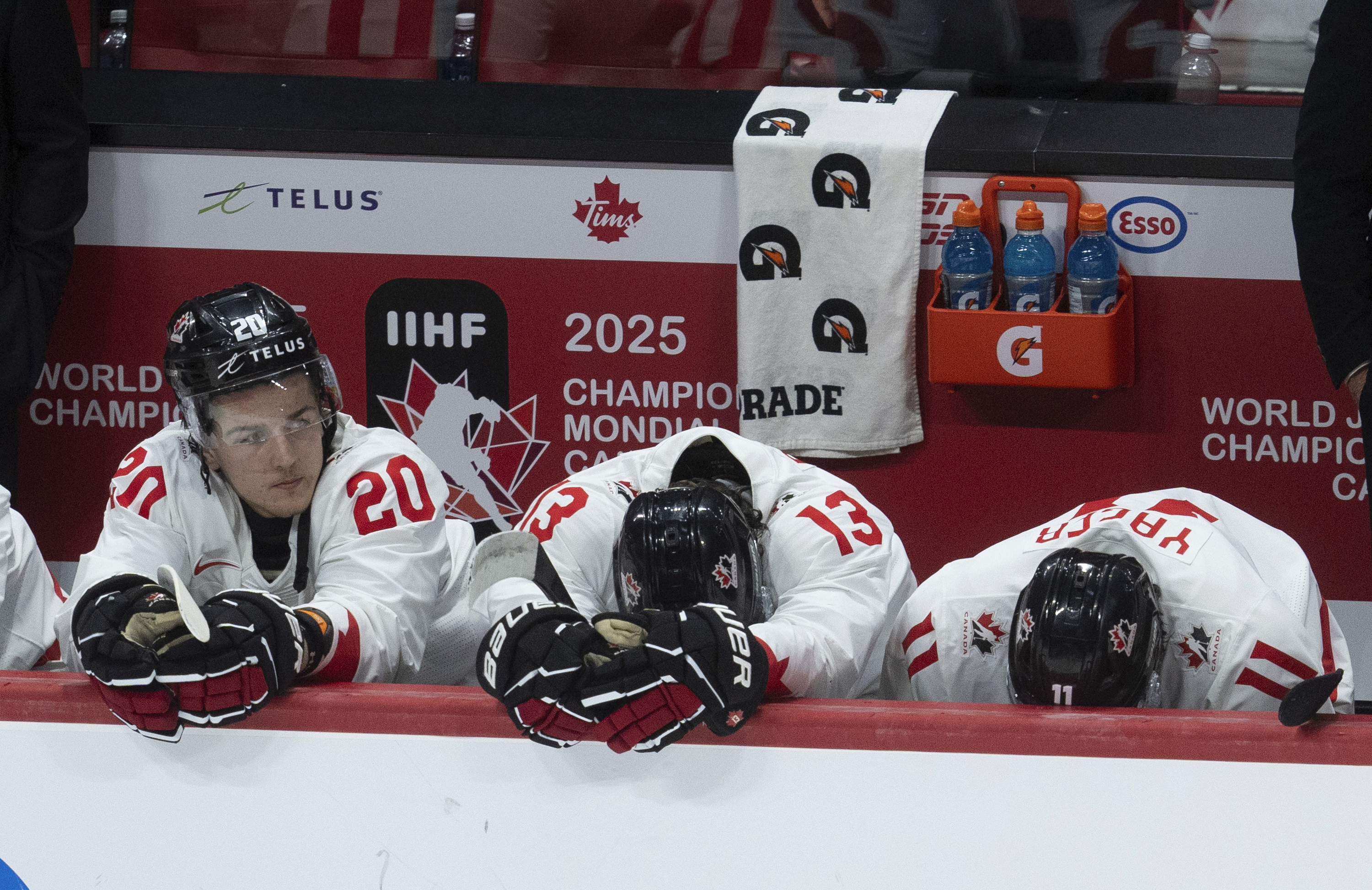 Canada forward Ethan Gauthier (20) sits on the bench alongside teammates Luca Pinelli (13) and Brayden Yager (11) during the third period of a quarterfinal match at the world junior hockey championship against Czech Republic in Ottawa, Ontario, Thursday, Jan. 2, 2025. (Adrian Wyld/The Canadian Press via AP)