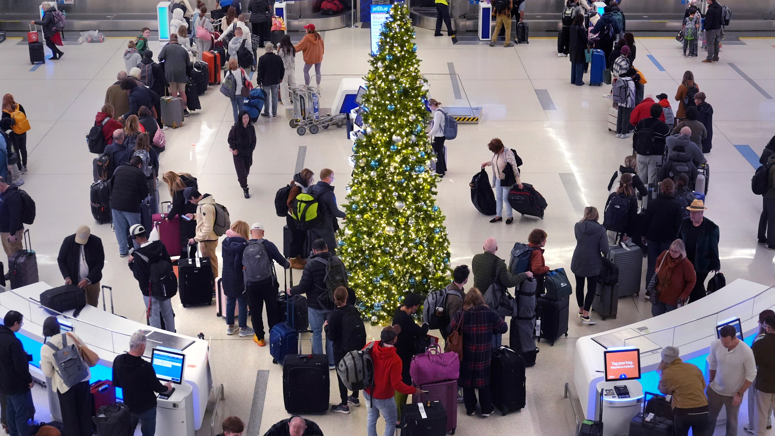 Holiday travelers wait in line to check their bags at the JetBlue terminal at Logan Airport, Friday, Dec. 20, 2024, in Boston. (AP Photo/Charles Krupa)