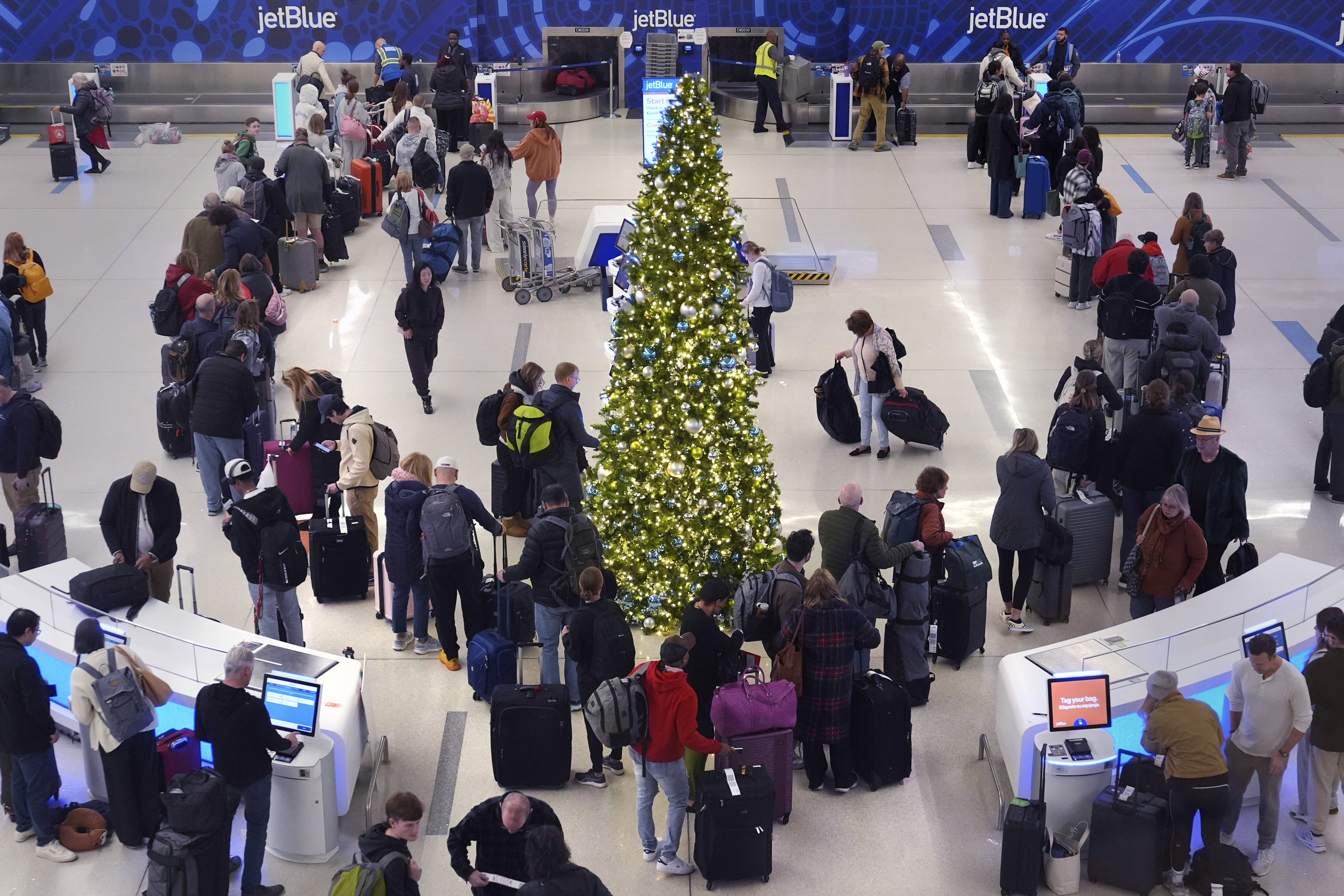 Holiday travelers wait in line to check their bags at the JetBlue terminal at Logan Airport, Friday, Dec. 20, 2024, in Boston. (AP Photo/Charles Krupa)