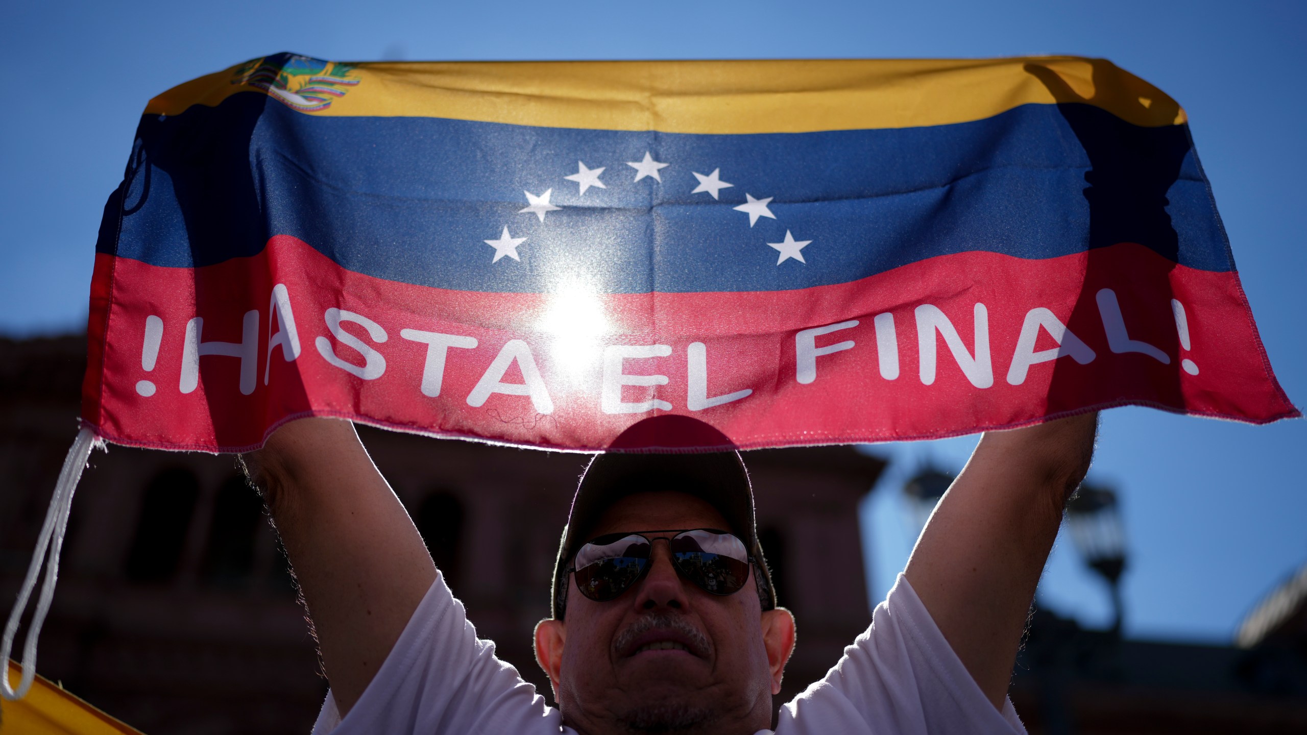 Leo Zambrano, supporter of Venezuela's opposition leader Edmundo Gonzalez Urrutia, holds a Venezuela's flag at Plaza de Mayo, outside the government house where he meets with Argentine President Javier Milei in Buenos Aires, Argentina, Saturday, Jan. 4, 2025. Gonzalez, who claims he won the 2024 presidential election and is recognized by some countries as the legitimate president-elect, traveled from exile in Madrid to Argentina. (AP Photo/Natacha Pisarenko)