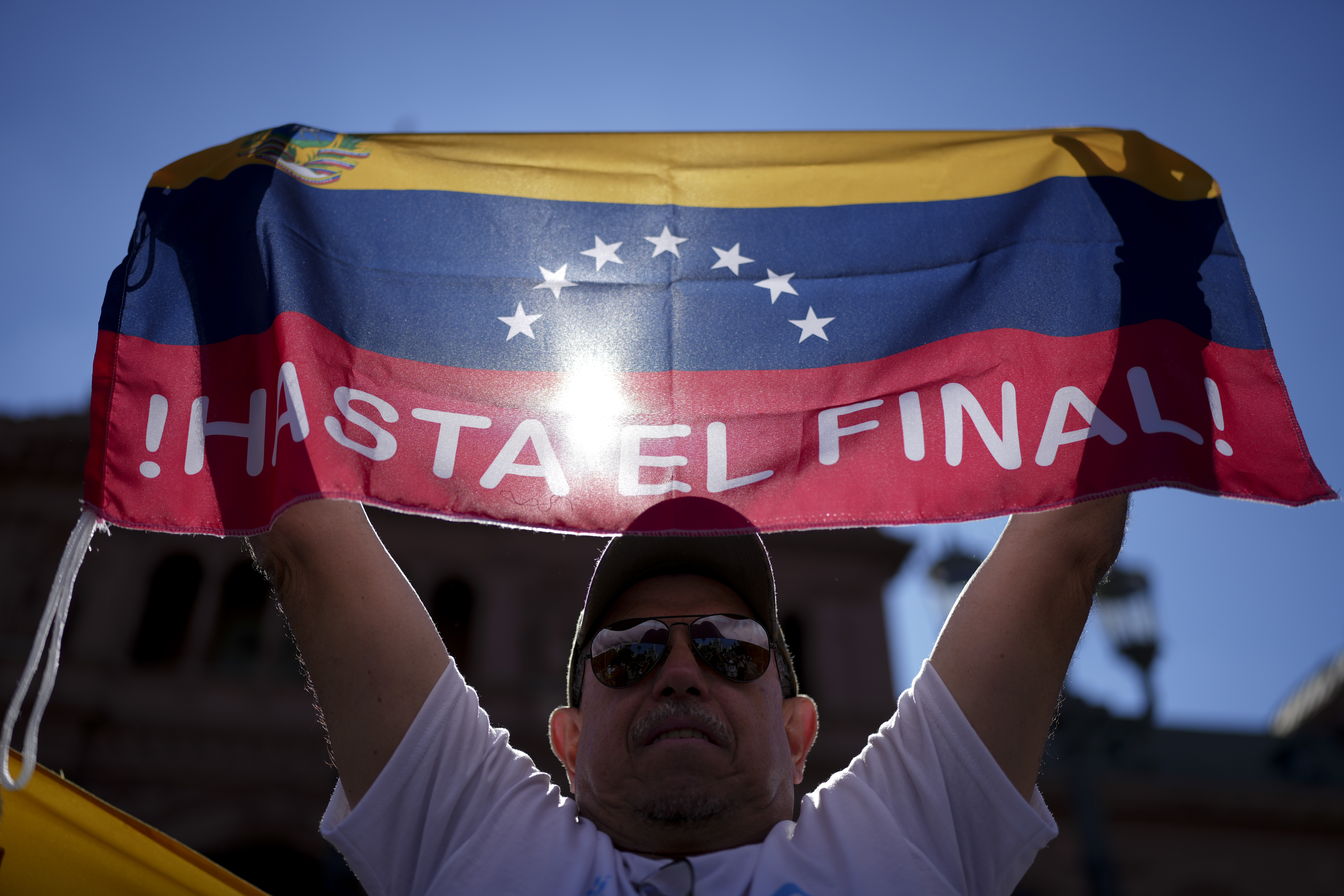 Leo Zambrano, supporter of Venezuela's opposition leader Edmundo Gonzalez Urrutia, holds a Venezuela's flag at Plaza de Mayo, outside the government house where he meets with Argentine President Javier Milei in Buenos Aires, Argentina, Saturday, Jan. 4, 2025. Gonzalez, who claims he won the 2024 presidential election and is recognized by some countries as the legitimate president-elect, traveled from exile in Madrid to Argentina. (AP Photo/Natacha Pisarenko)