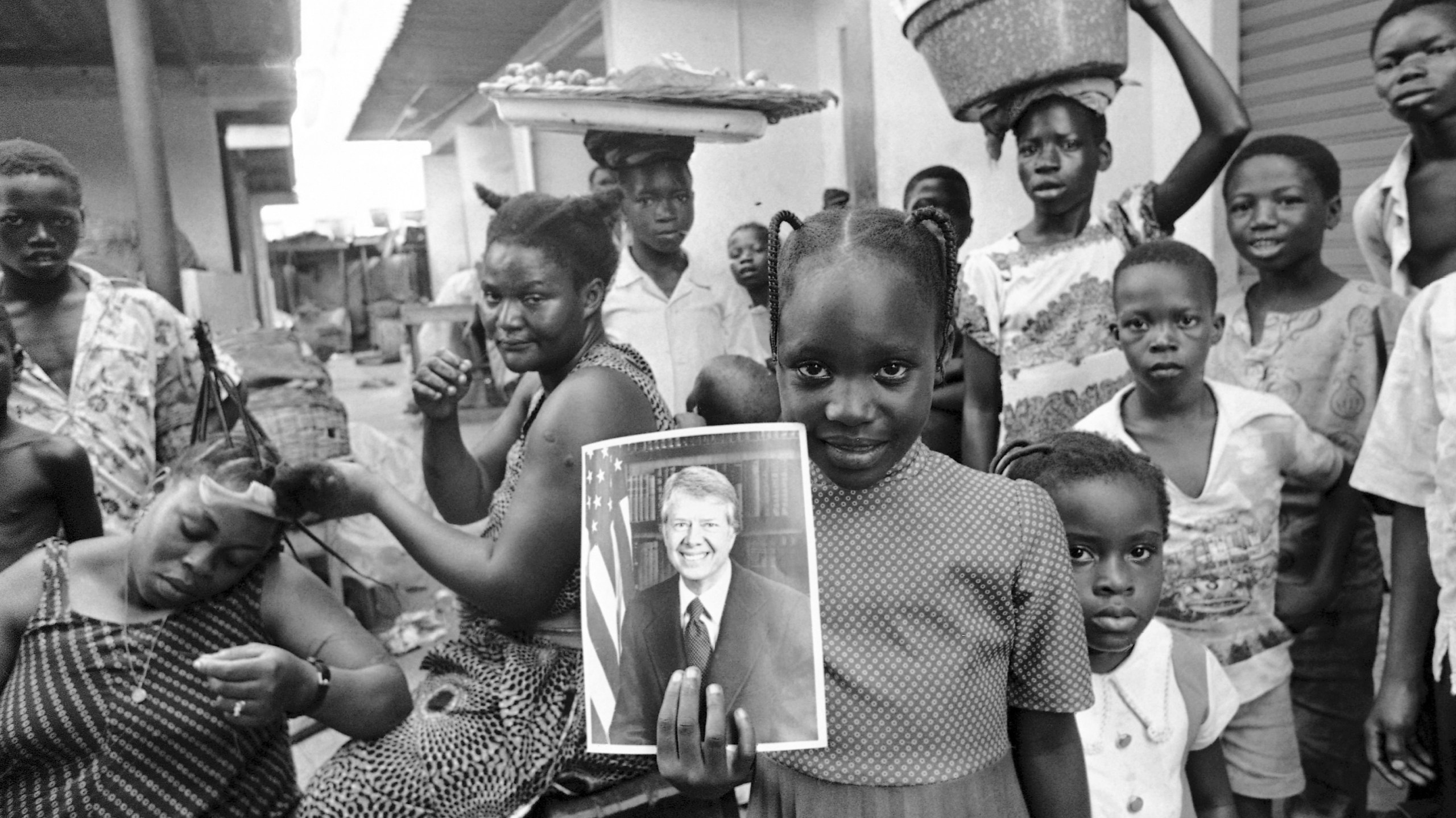 FILE - A girl holds a portrait of U.S. President Jimmy Carter in a market in Lagos, Nigeria, March 31, 1978, the day of his arrival for a state visit, the first to Africa by an American president. (AP Photo/Dieter Endlicher, File)