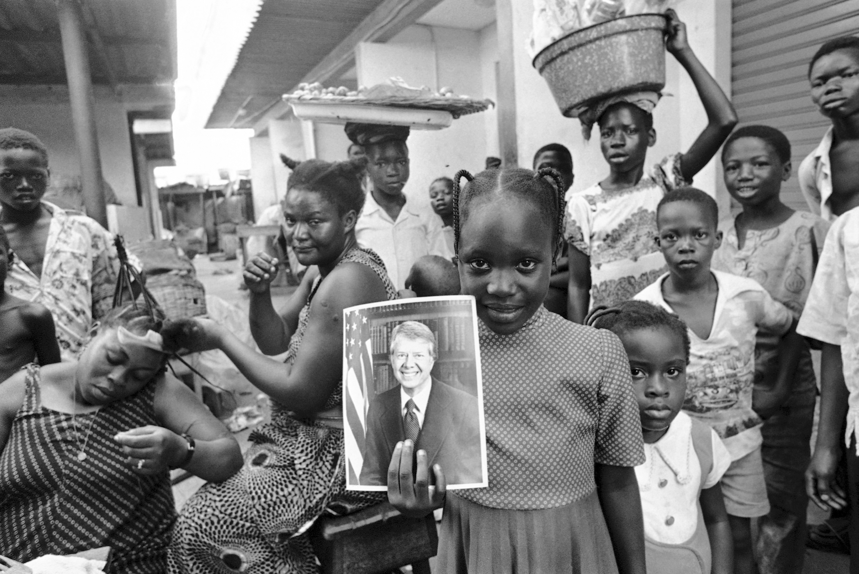 FILE - A girl holds a portrait of U.S. President Jimmy Carter in a market in Lagos, Nigeria, March 31, 1978, the day of his arrival for a state visit, the first to Africa by an American president. (AP Photo/Dieter Endlicher, File)