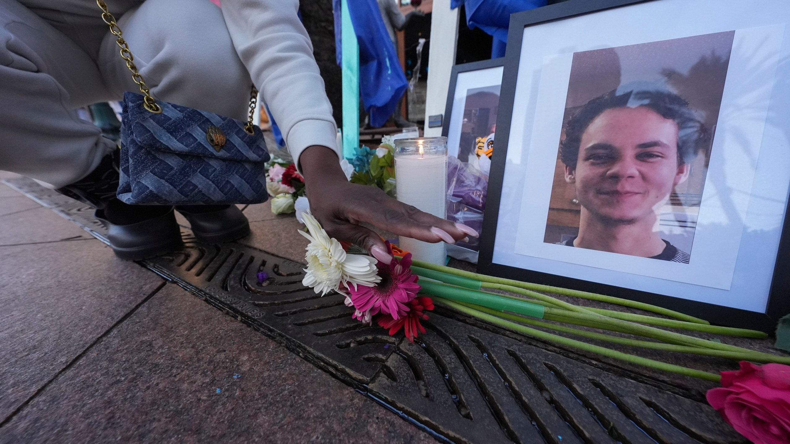 A woman places flowers next to photos of victim Matthew Tenedorio at memorial on Canal Street for the victims of a deadly truck attack on New Year's Day in New Orleans, Friday, Jan. 3, 2025. (AP Photo/Gerald Herbert)