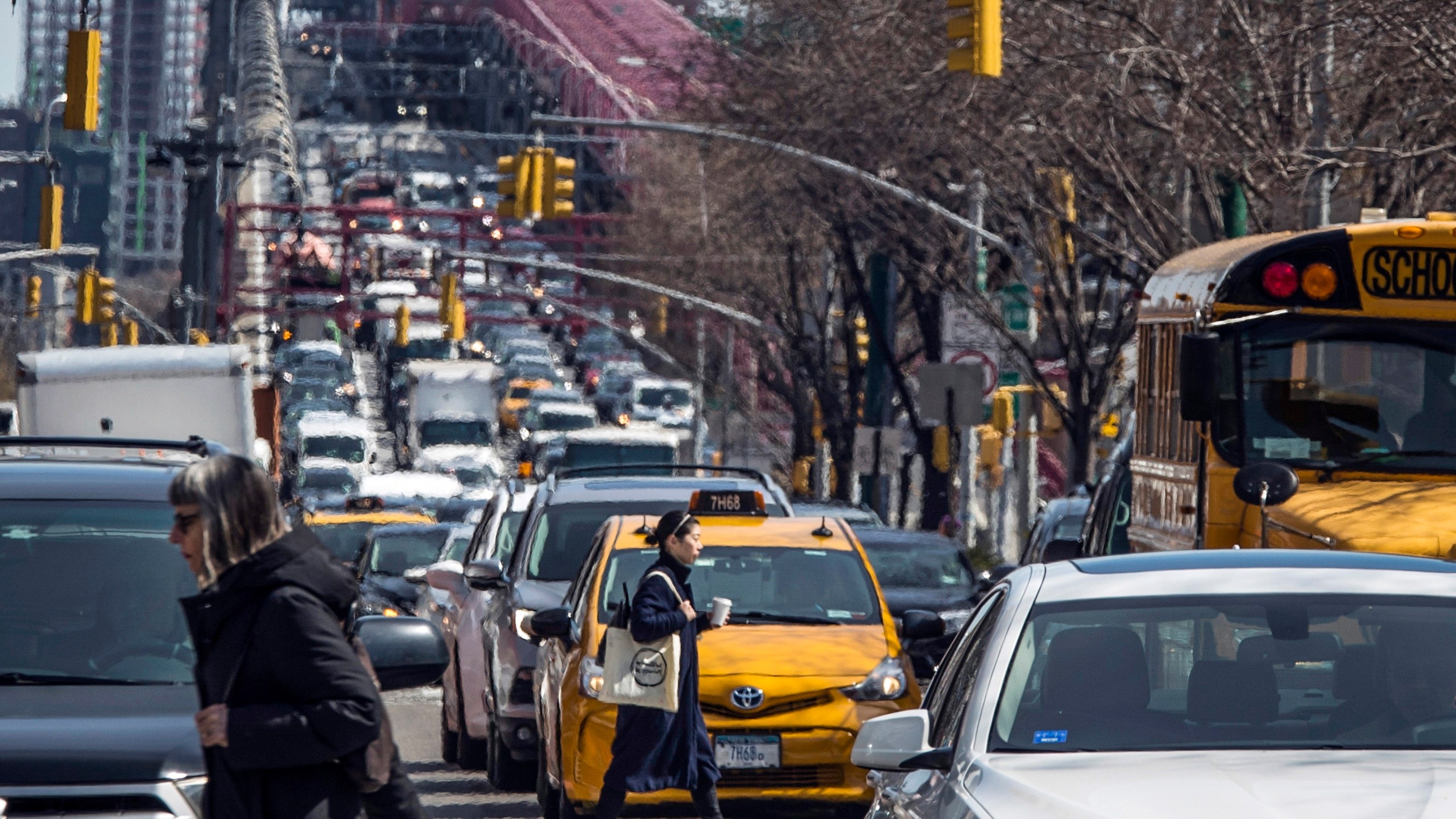 FILE - Pedestrians cross Delancey Street as congested traffic from Brooklyn enters Manhattan over the Williamsburg Bridge, March 28, 2019, in New York. (AP Photo/Mary Altaffer, File)