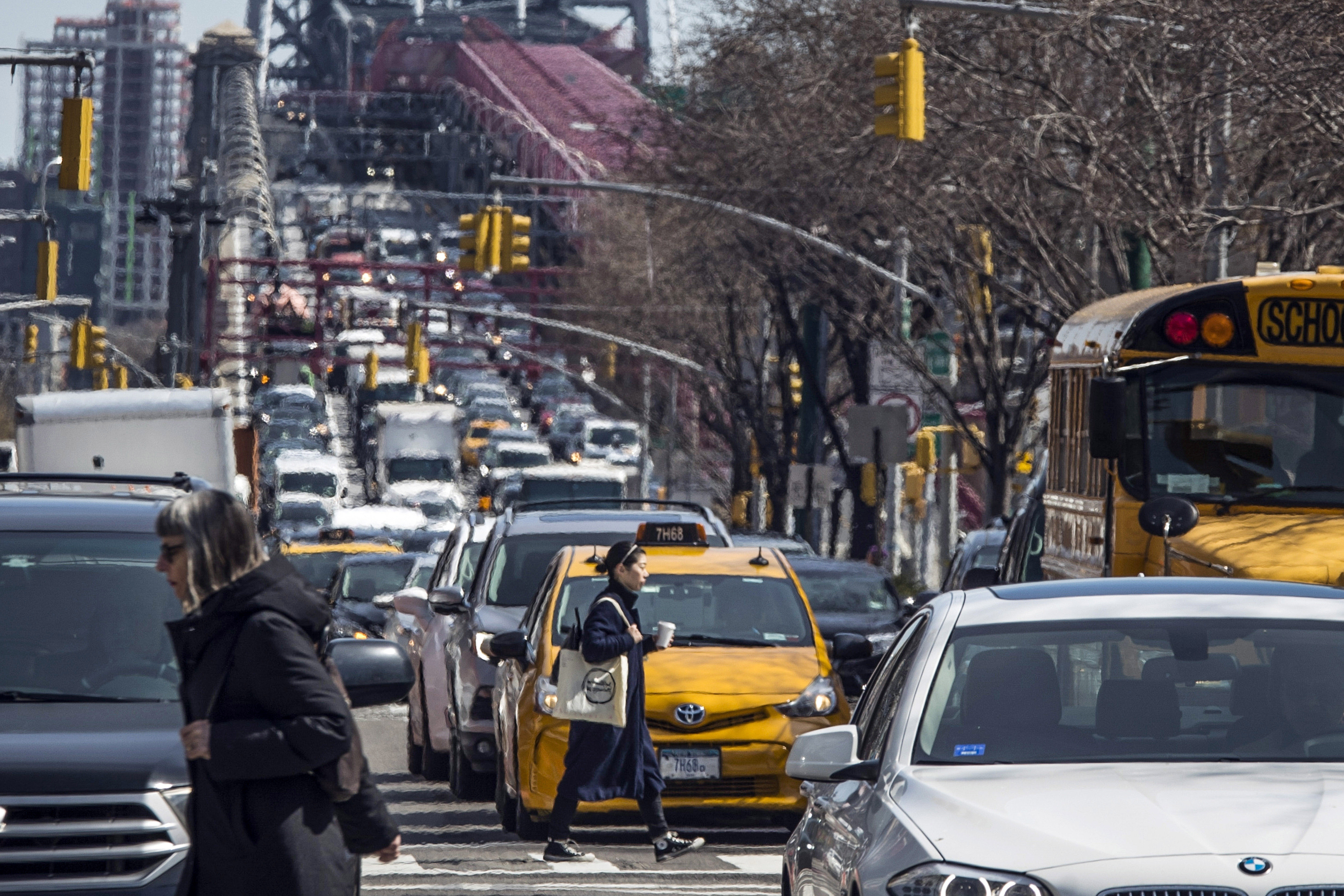 FILE - Pedestrians cross Delancey Street as congested traffic from Brooklyn enters Manhattan over the Williamsburg Bridge, March 28, 2019, in New York. (AP Photo/Mary Altaffer, File)