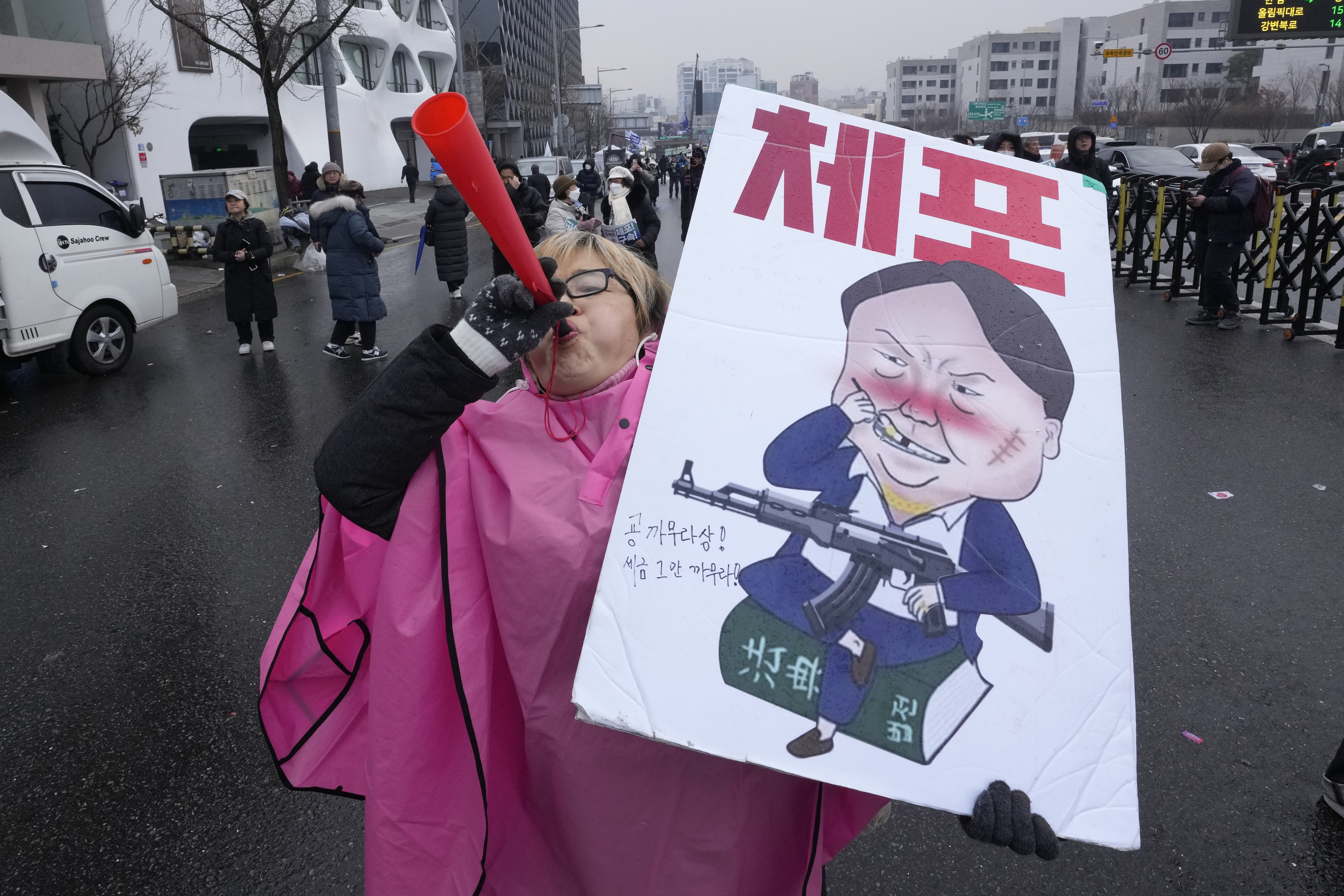 A protester blows a vuvuzela during a rally demanding the arrest of impeached South Korean President Yoon Suk Yeol near the presidential residence in Seoul, South Korea, Monday, Jan. 6, 2025. The letters read "Arrest Yoon Suk Yeol." (AP Photo/Ahn Young-joon)