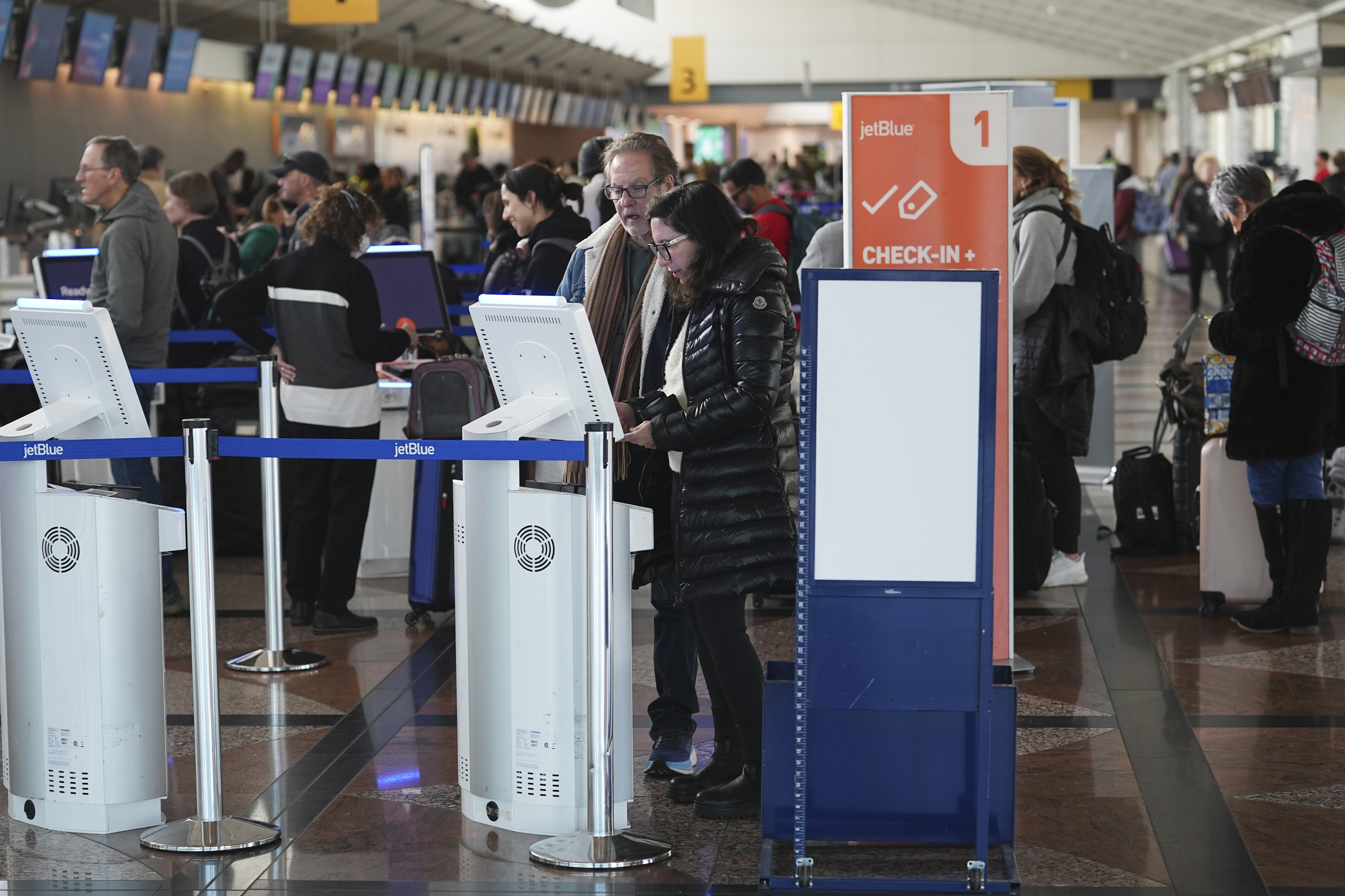 Travellers queue up at the Jet Blue Airlines self-check-in kiosks in Denver International Airport Tuesday, Dec. 24, 2024, in Denver. (AP Photo/David Zalubowski)