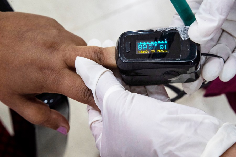 FILE - A health worker uses a pulse oximeter to check the oxygen saturation level of another after administering COVID-19 vaccine at a hospital in Gauhati, India, Jan. 21, 2021. (AP Photo/Anupam Nath, File)