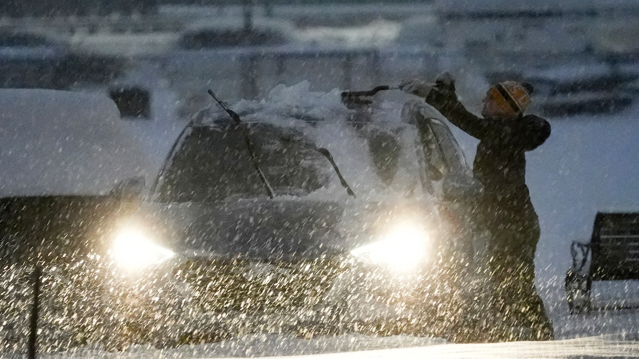 A person clears off a car during a winter snow storm in Washington, Monday, Jan. 6, 2025. (AP Photo/Matt Rourke)