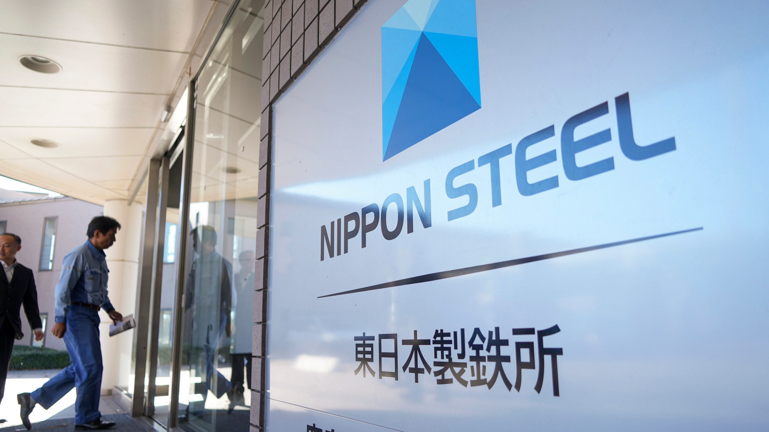 FILE - A staff enters doorway next to Nippon Steel logo at the company's Kashima Plant in Kashima, Japan on Friday, Dec. 6, 2024. (AP Photo/Ayaka McGill, File)