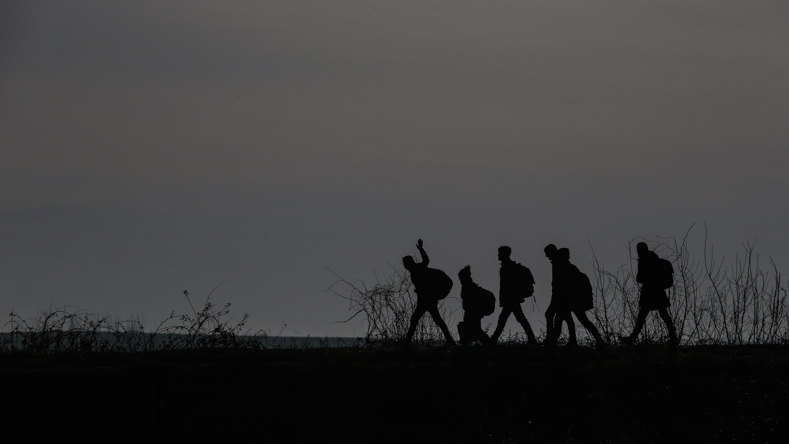 FILE - Migrants walk to enter Greece from Turkey by crossing the Maritsa river (Evros river in Greek) near the Pazarkule border gate in Edirne, Turkey, March 1, 2020. (AP Photo/Emrah Gurel, File)