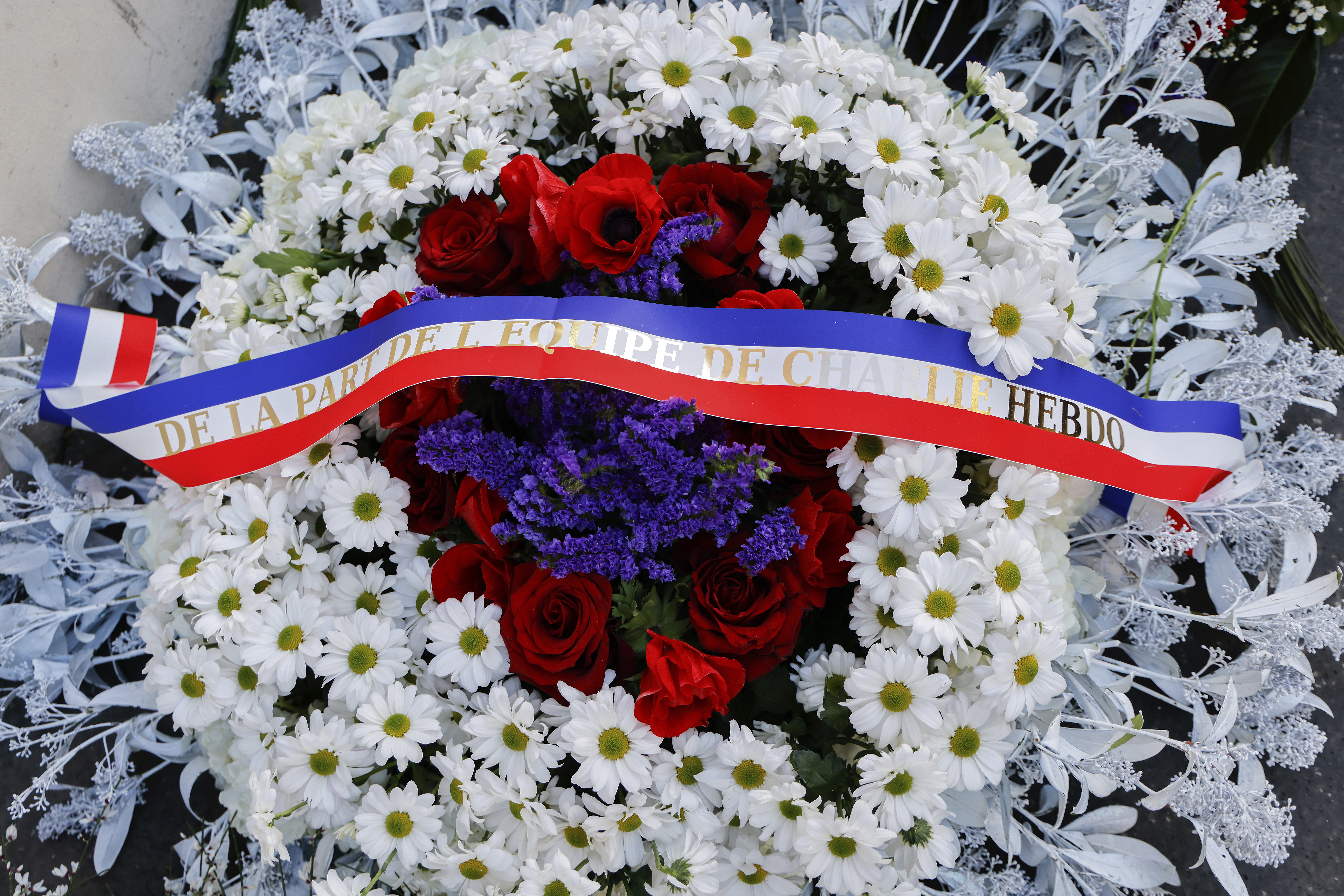 A wreath of flowers from Charlie Hebdo magazine is seen during a commemoration marking 10 years since an Islamist attack on the Charlie Hebdo satirical newspaper and the Hypercacher jewish supermarket, outside the weekly's former offices in Paris Tuesday Jan. 7, 2025. A decade after gunmen stormed the offices of satirical newspaper Charlie Hebdo in a deadly assault that shook France to its core, the nation is pausing to honor the victims and grapple with the evolving challenges of free expression and terrorism. (Ludovic Marin, Pool via AP)