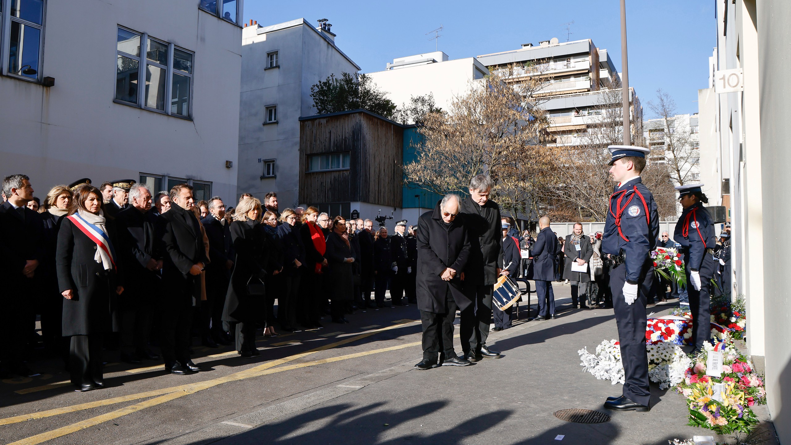 French President Emmanuel Macron, fourth left,his wife, Brigitte Macron, fifth left, France's Prime minister Francois Bayrou, third left, and Mayor of Paris Anne Hidalgo, left, stand next to French satirical magazine "Charlie Hebdo" editor in chief Gerard Biard , center left, and publishing director Laurent Sourisseau, known as "Riss", center right, during a commemoration marking 10 years since an Islamist attack on the Charlie Hebdo satirical newspaper and the Hypercacher jewish supermarket, outside the weekly's former offices in Paris Tuesday Jan. 7, 2025. (Ludovic Marin, Pool via AP)