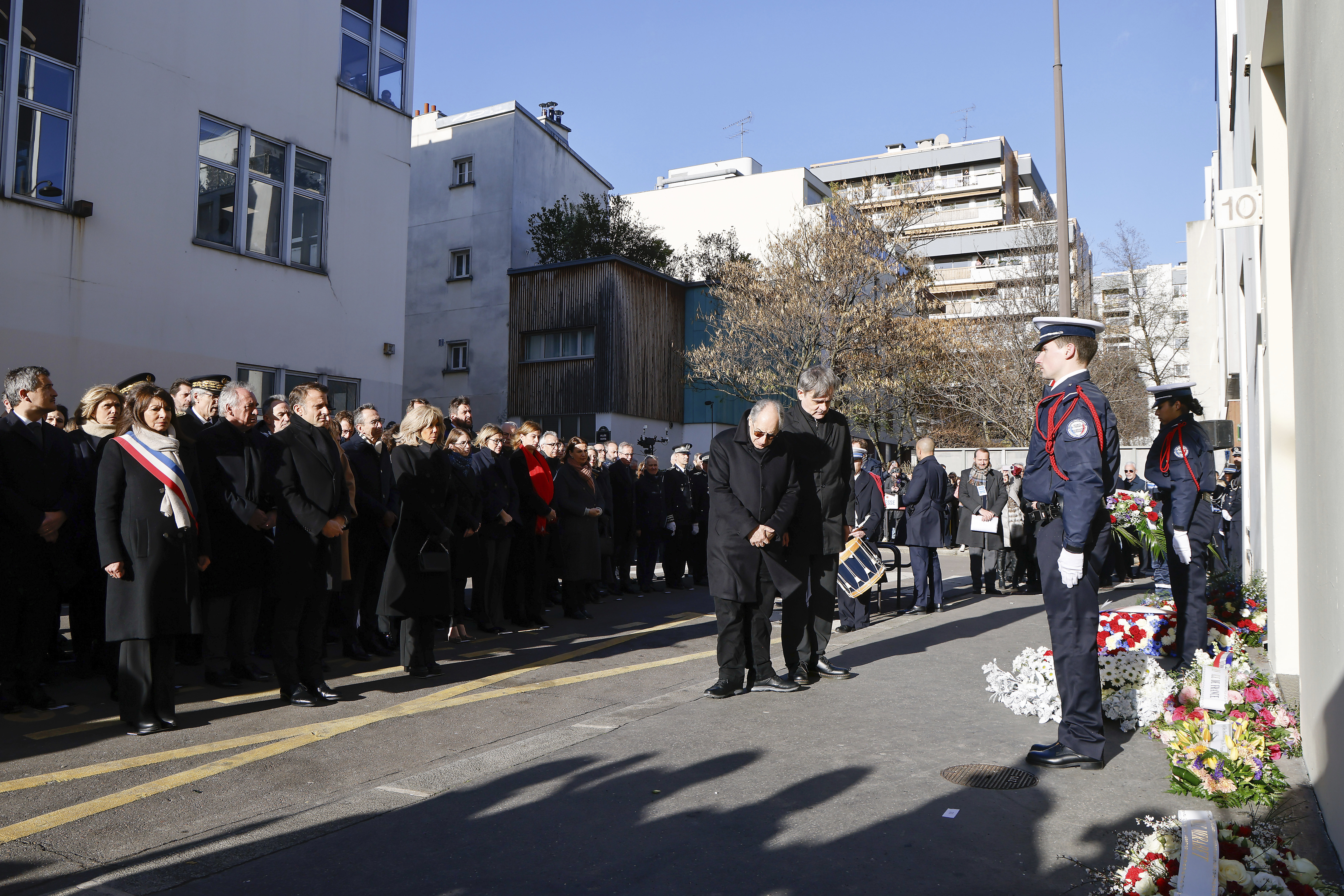 French President Emmanuel Macron, fourth left,his wife, Brigitte Macron, fifth left, France's Prime minister Francois Bayrou, third left, and Mayor of Paris Anne Hidalgo, left, stand next to French satirical magazine "Charlie Hebdo" editor in chief Gerard Biard , center left, and publishing director Laurent Sourisseau, known as "Riss", center right, during a commemoration marking 10 years since an Islamist attack on the Charlie Hebdo satirical newspaper and the Hypercacher jewish supermarket, outside the weekly's former offices in Paris Tuesday Jan. 7, 2025. (Ludovic Marin, Pool via AP)