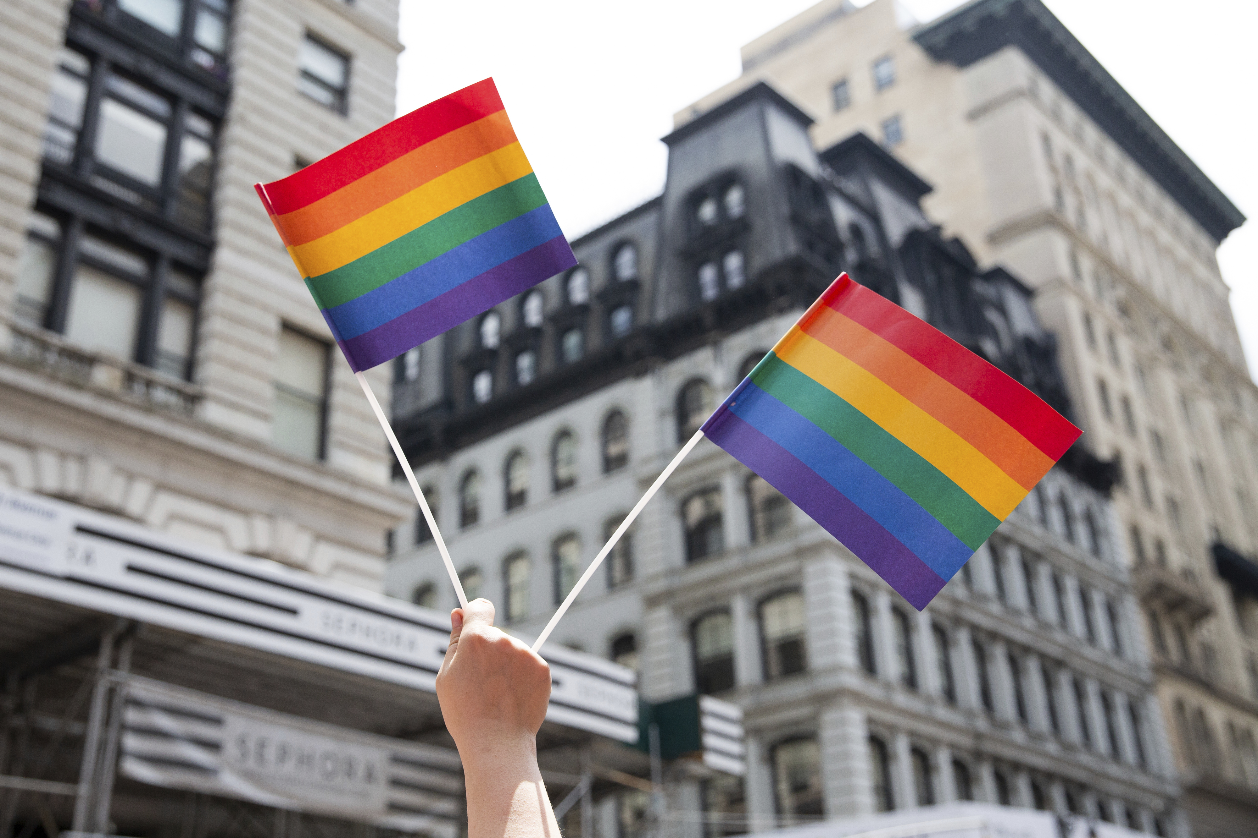 FILE - A person holds up LGTBQ+ pride flags during the Pride Parade in New York, June 24, 2018. (AP Photo/Steve Luciano, File)